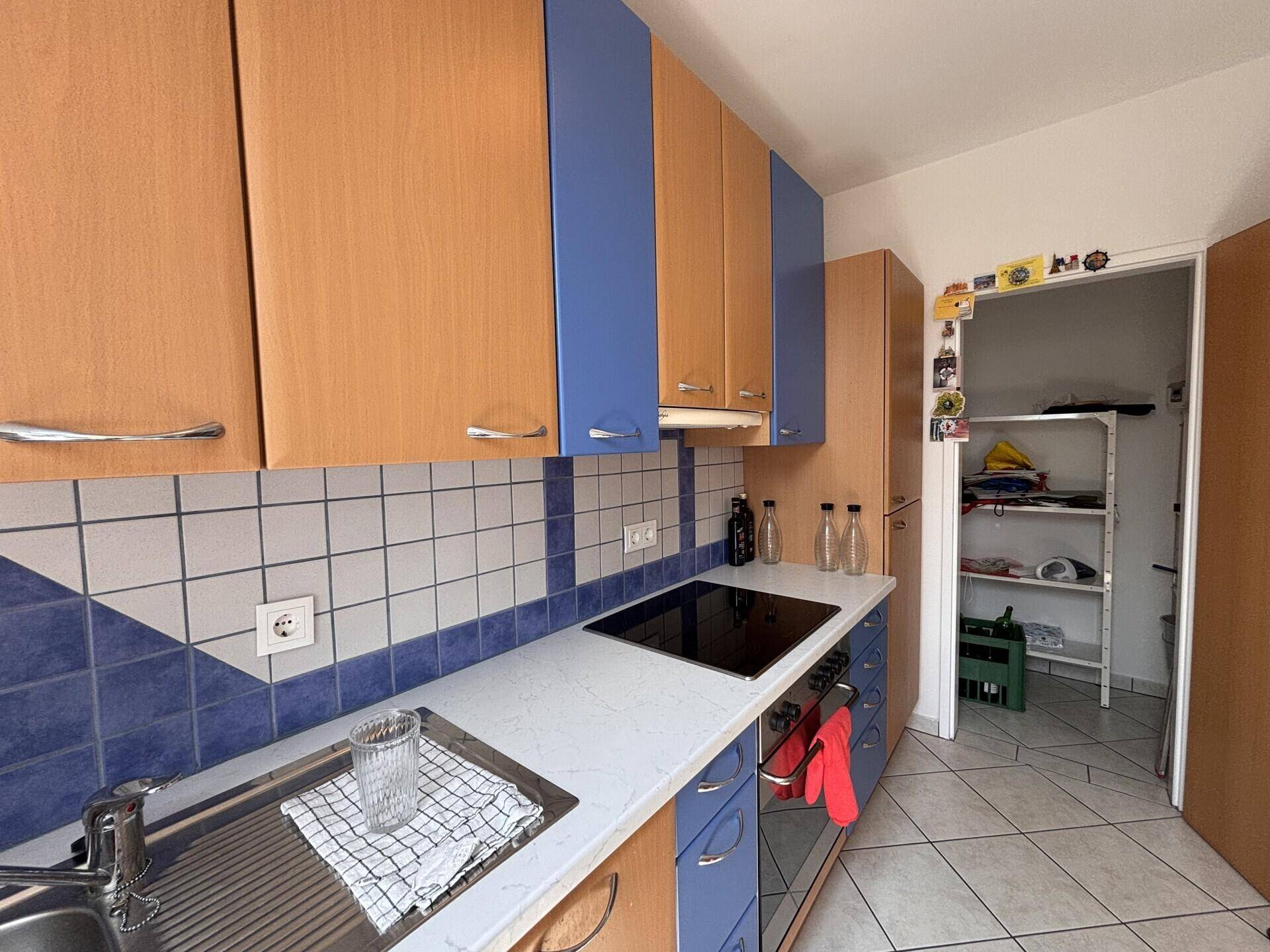 Küche mit Spülbereich, Induktionskochfeld und Zugang zu einem praktischen Abstellraum.