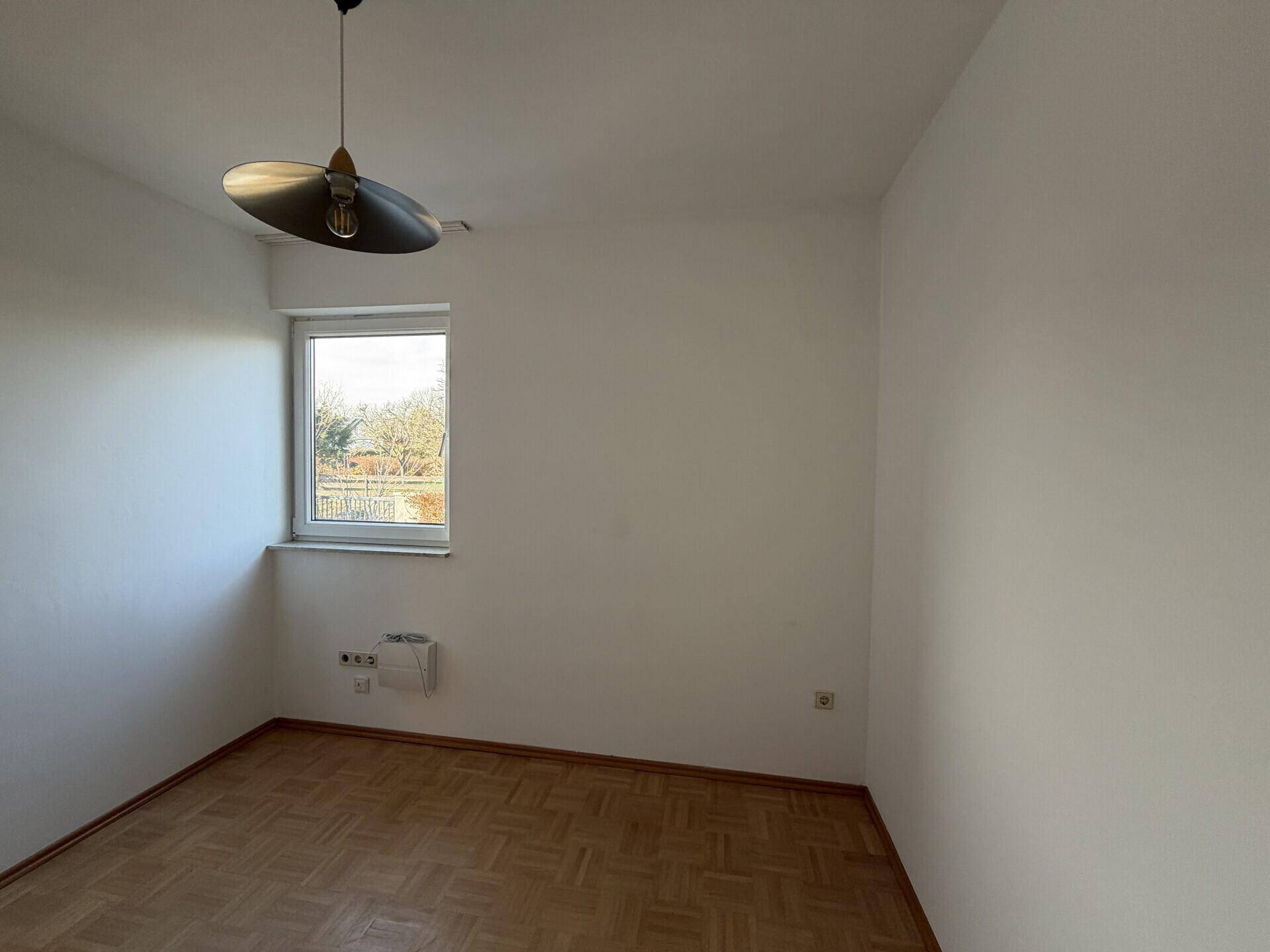 Kleiner, heller Raum mit Parkettboden und Fenster, ideal als Kinder- oder Arbeitszimmer.