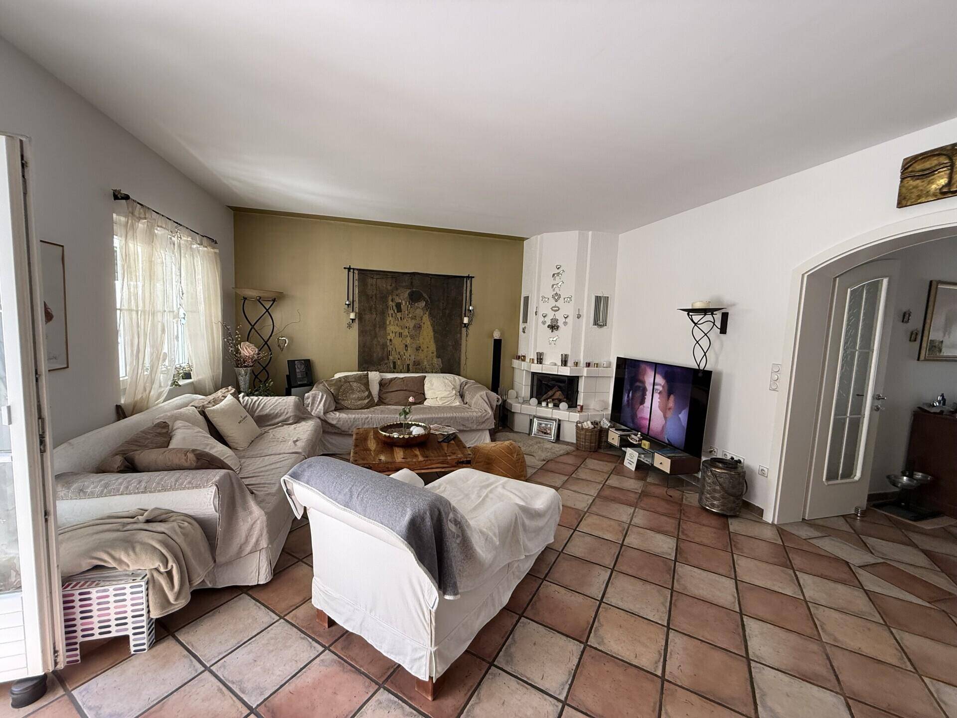 Gemütliches Wohnzimmer mit Terrakottafliesen, Kamin und bequemen Sofas.