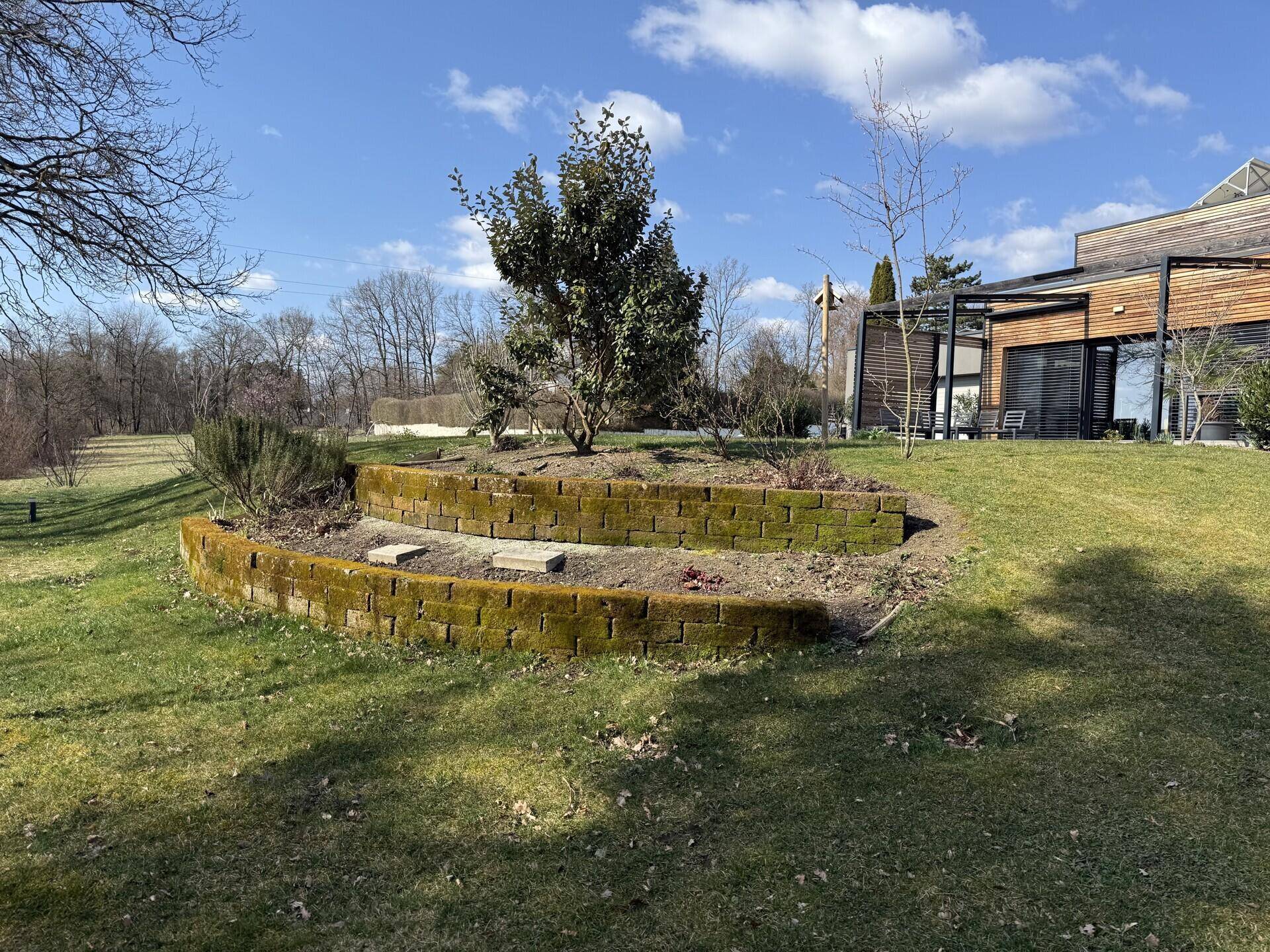 Gepflegter Gartenbereich mit einer gemauerten Blumenbeet-Einfassung und Rasenfläche.