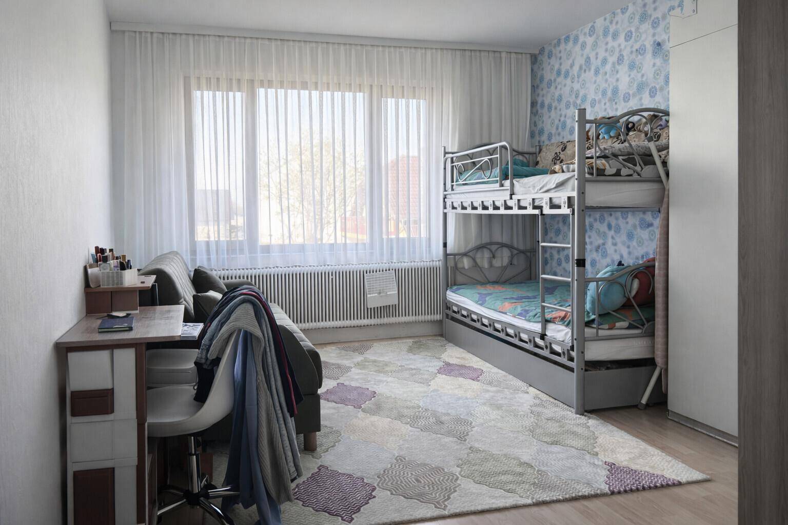 Kinderzimmer mit Etagenbett, Schreibtisch und großen Fenstern für viel Tageslicht.