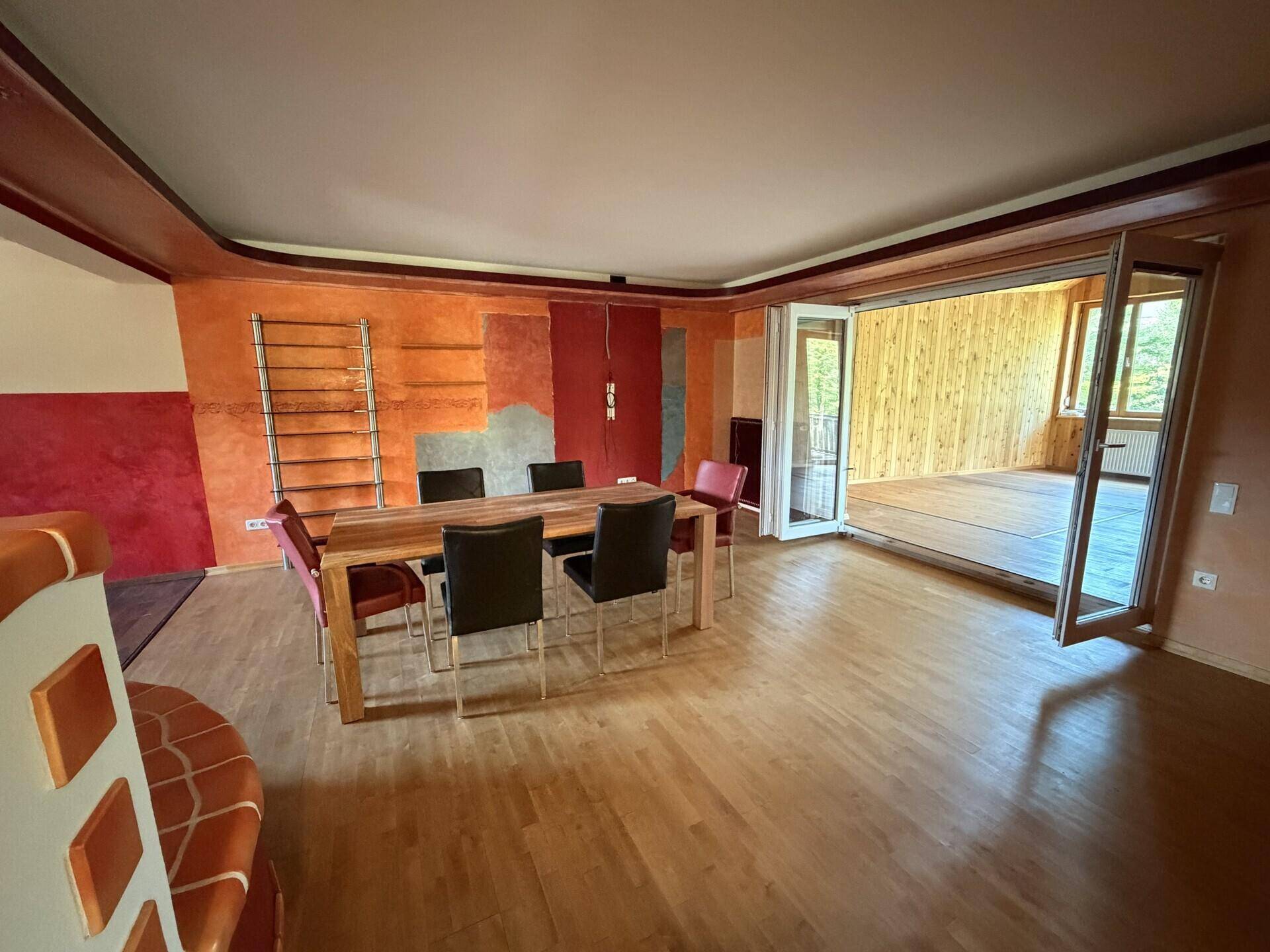 Heller Essbereich mit Holztisch und Zugang zu einem verglasten Anbau, der viel Licht spendet.