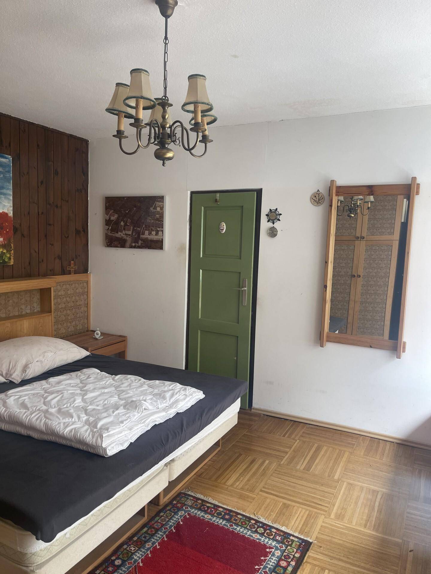 Schlafzimmer mit Holzboden und traditioneller Einrichtung, inklusive Deckenleuchte.
