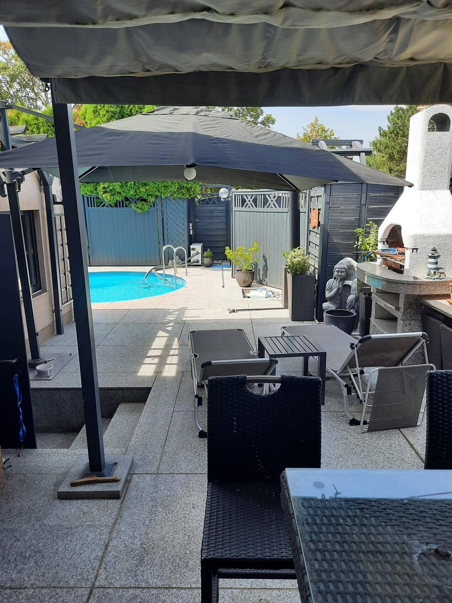 Großzügige Terrasse mit bequemen Sitzmöbeln, einem Pool und einer praktischen Außenküche mit Grill.