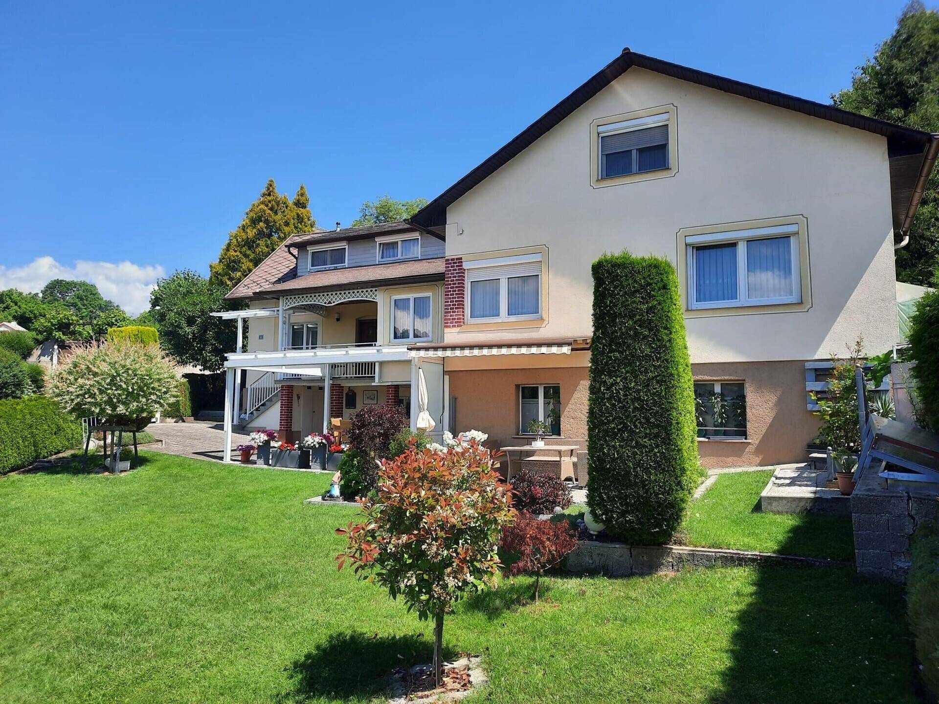 Weitläufiger Garten mit Rasenfläche und Blick auf die Rückseite des Hauses.