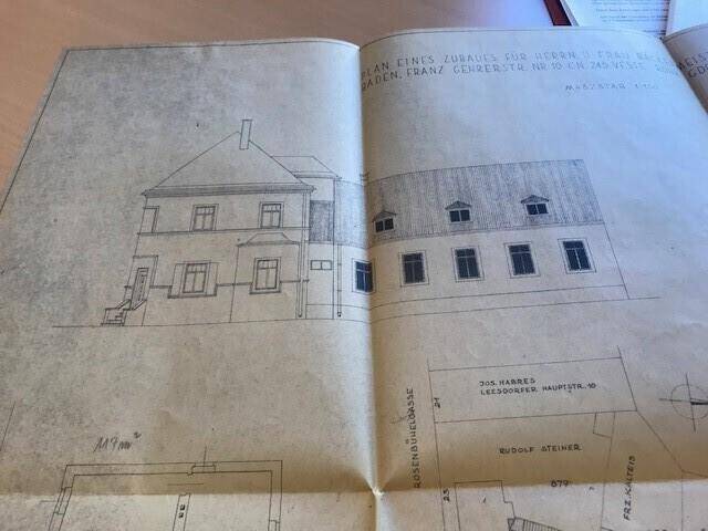 Historische Ansicht eines Gebäudes mit mehreren Stockwerken und einem Anbau.