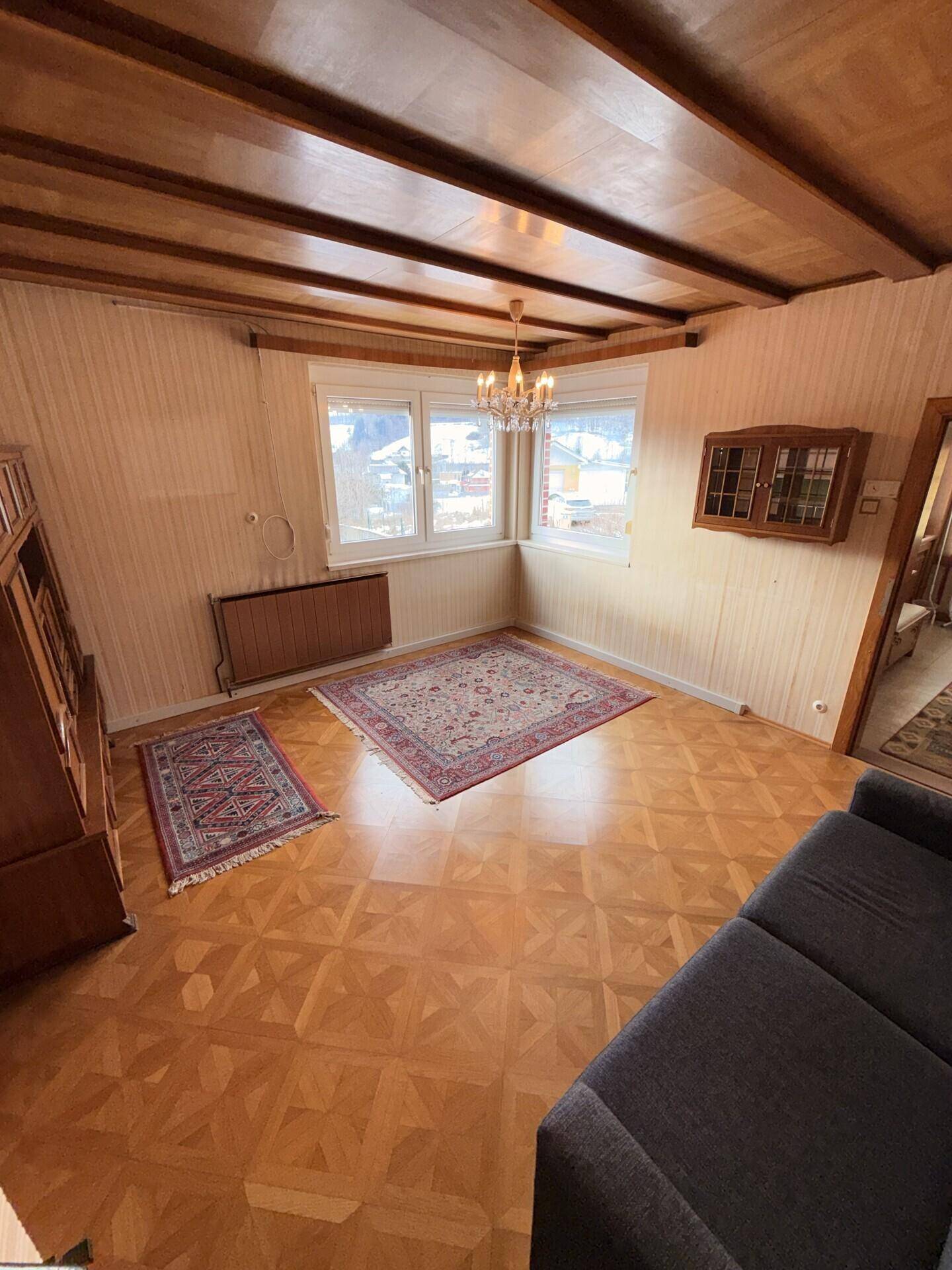 Wohnzimmer mit Parkettboden, Holzdecke und Erkerfenster, bietet viel Tageslicht.