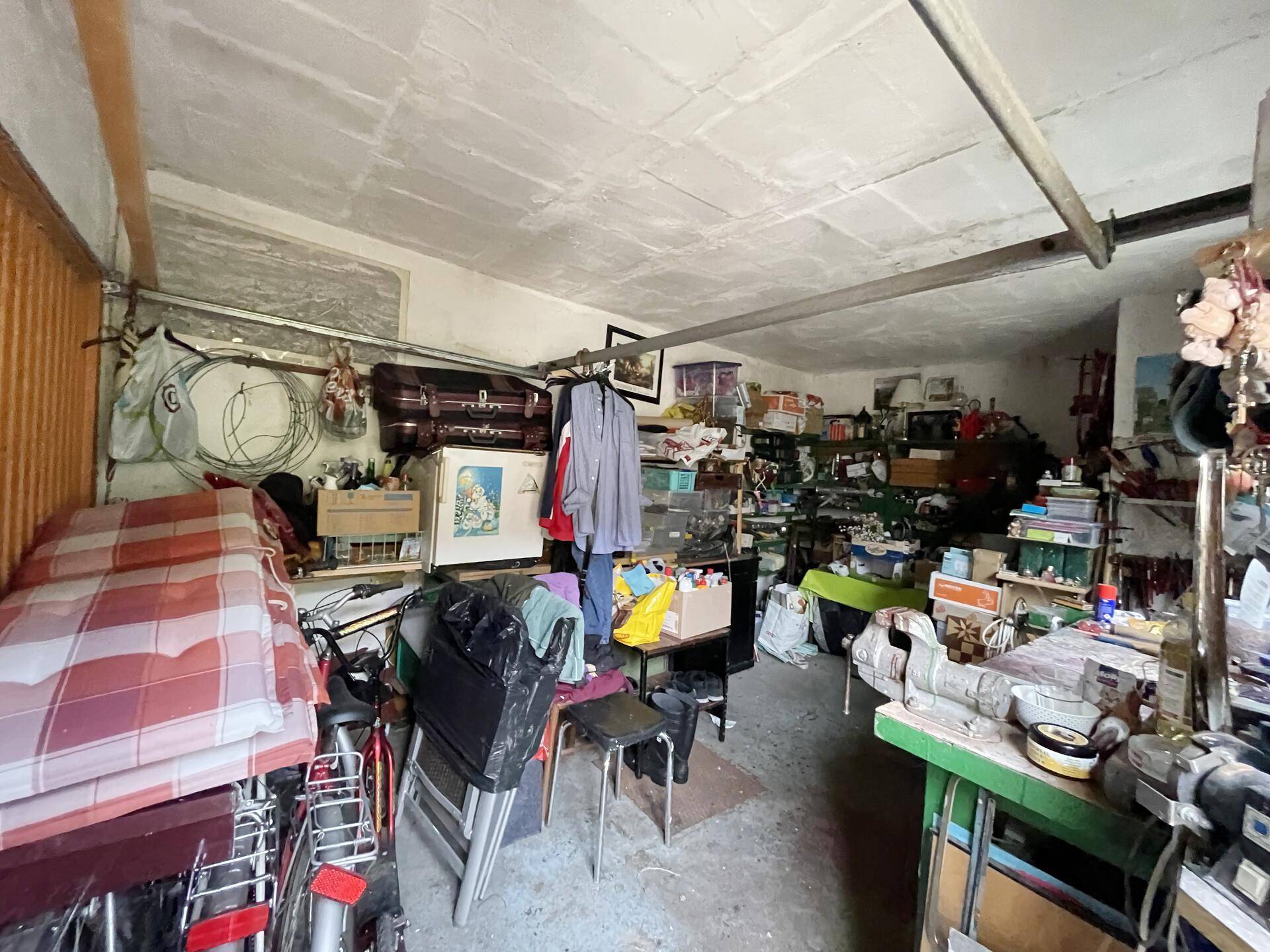 Geräumige Garage oder Werkstatt mit viel Stauraum und verschiedenen Gegenständen.