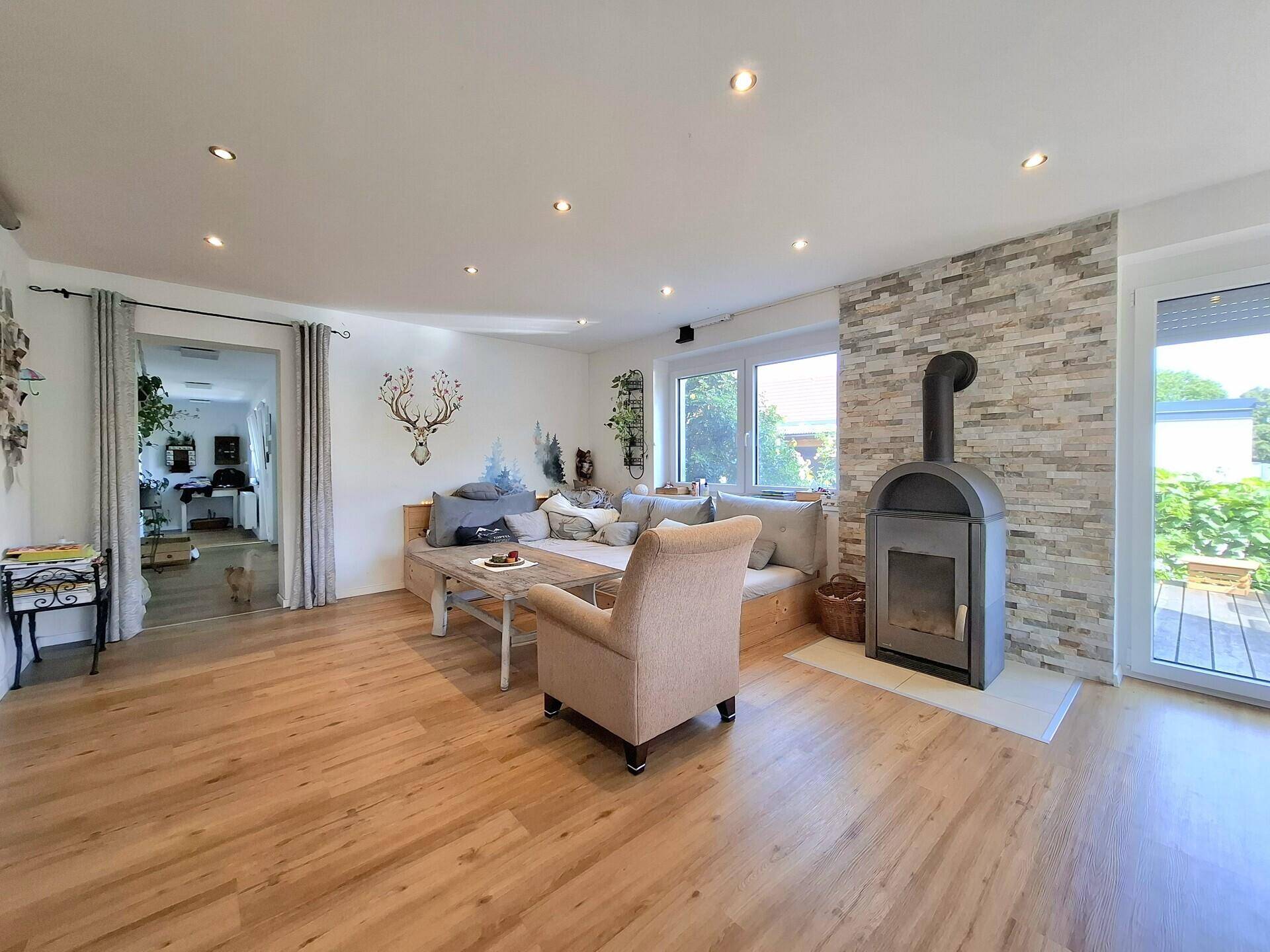 Geräumiges Wohnzimmer mit Holzboden, Kamin und Zugang zu weiteren Räumen.