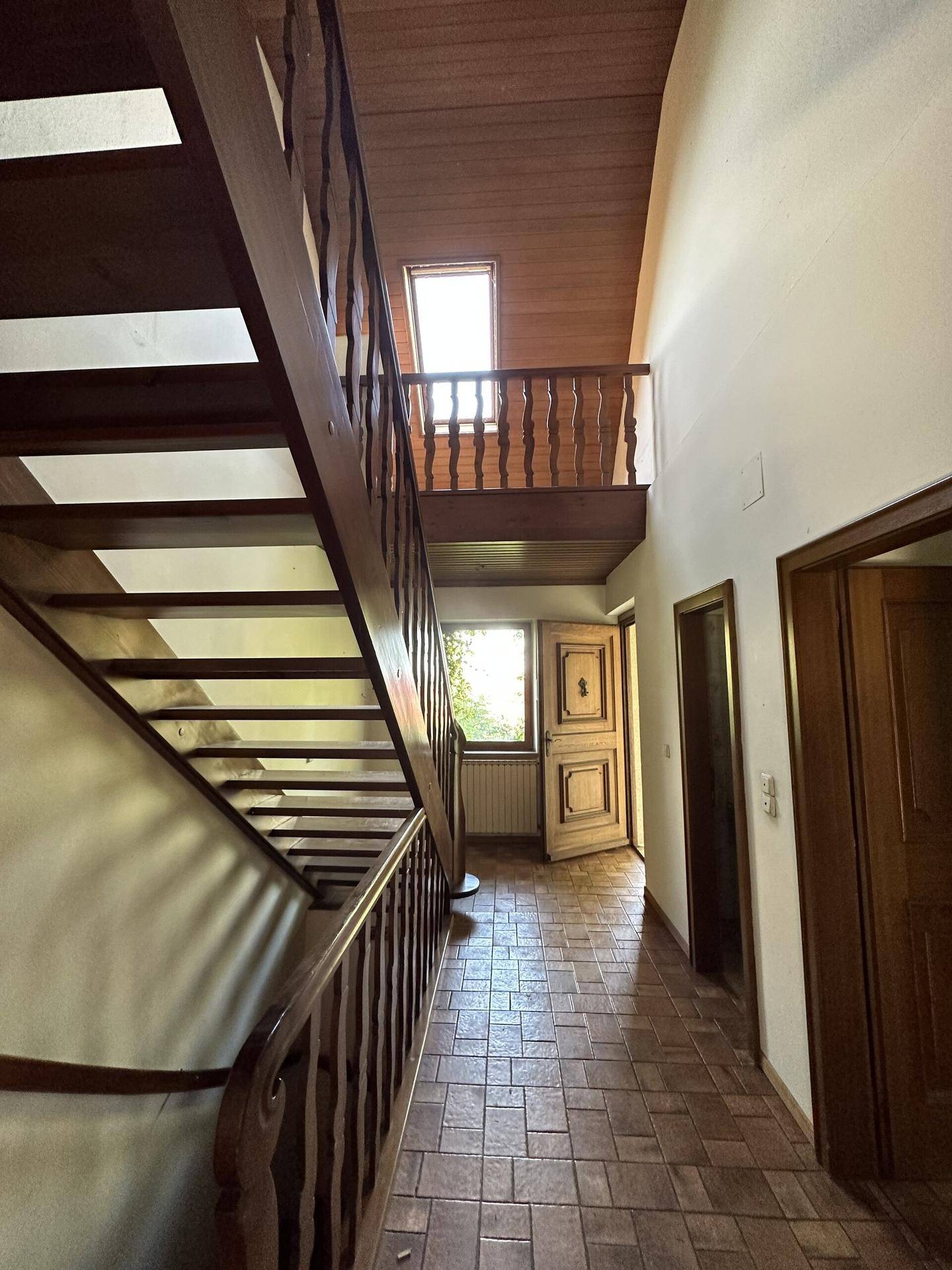 Geräumiger Flur mit Holztreppe und Holzbalkendecke, die zu den oberen Etagen führt, mit Fliesenboden.