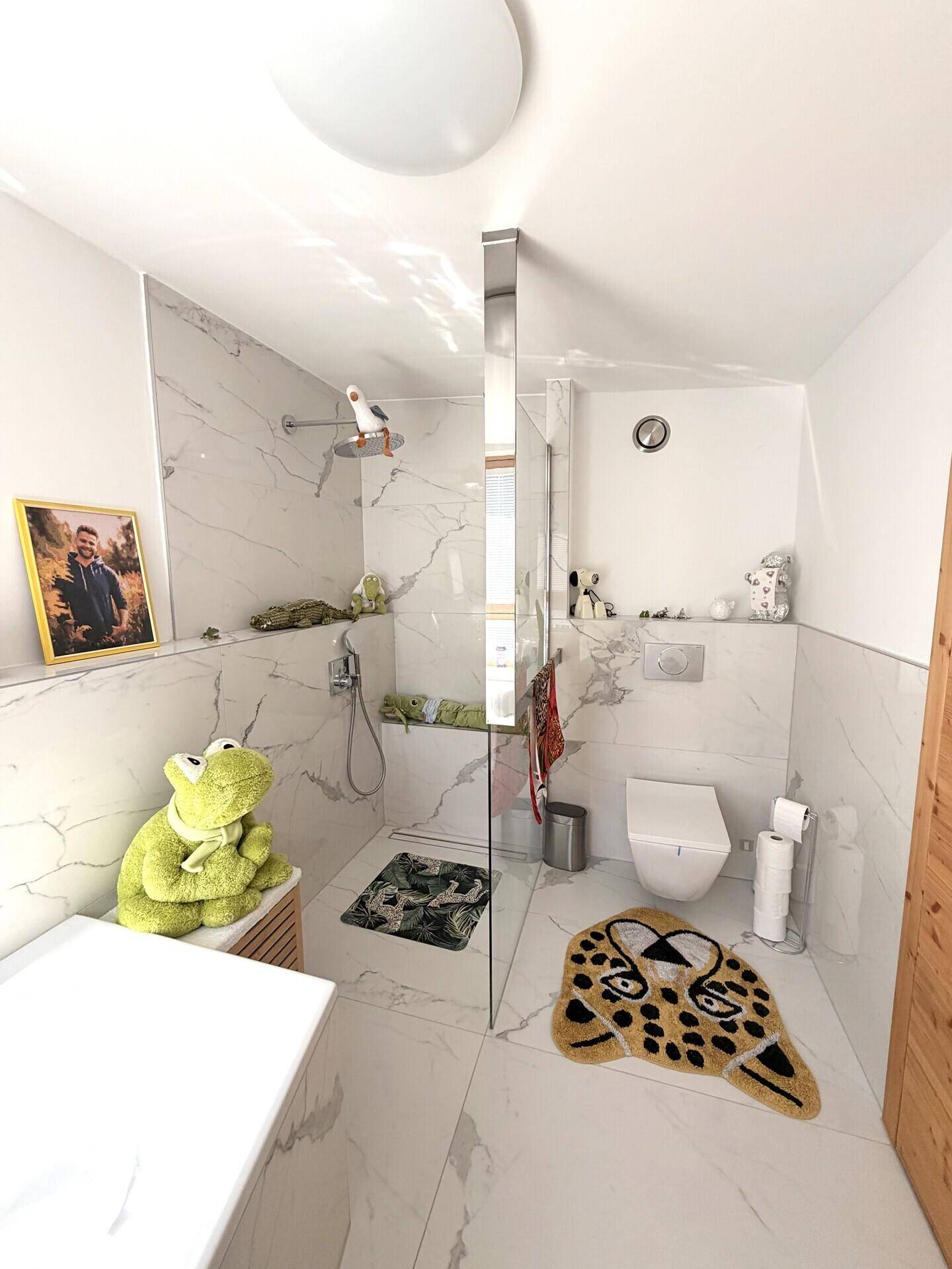 Modernes Badezimmer mit begehbarer Dusche, weißen Marmorfliesen und Wand-WC.