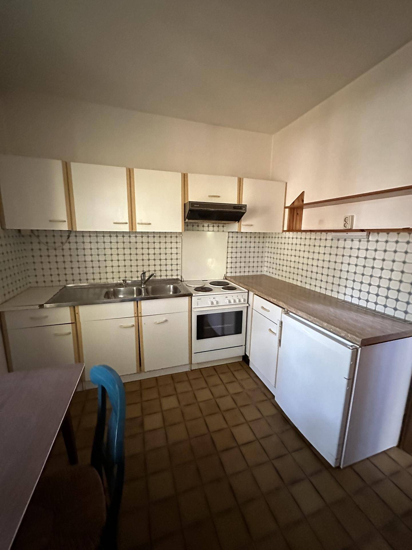 Kleine, funktionale Küche mit weißen Schränken, Elektroherd und Kühlschrank, im traditionellen Stil.