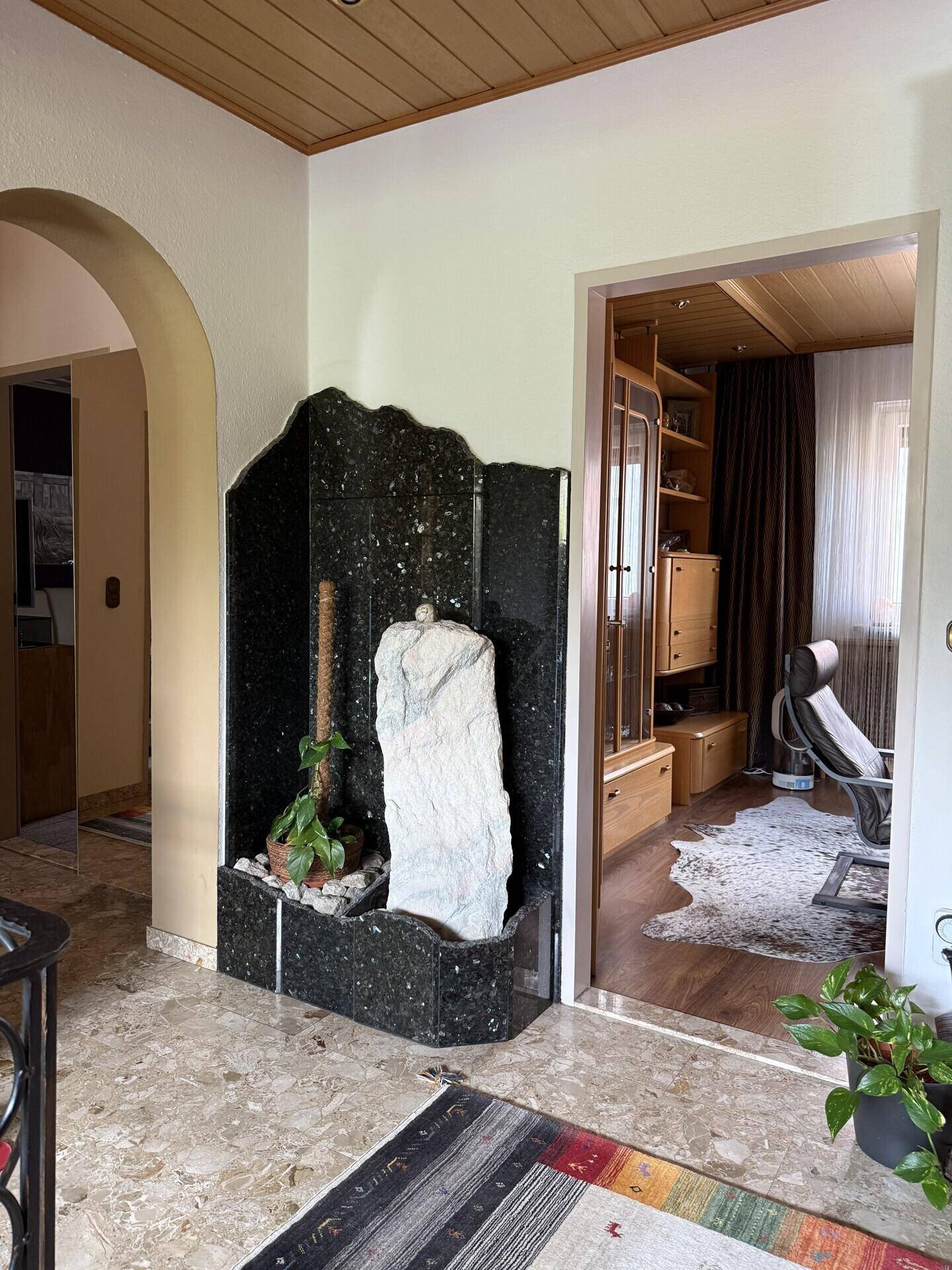 Eingangsbereich mit Marmorboden, dekorativem Steinbrunnen und Zugang zu weiteren Räumen.
