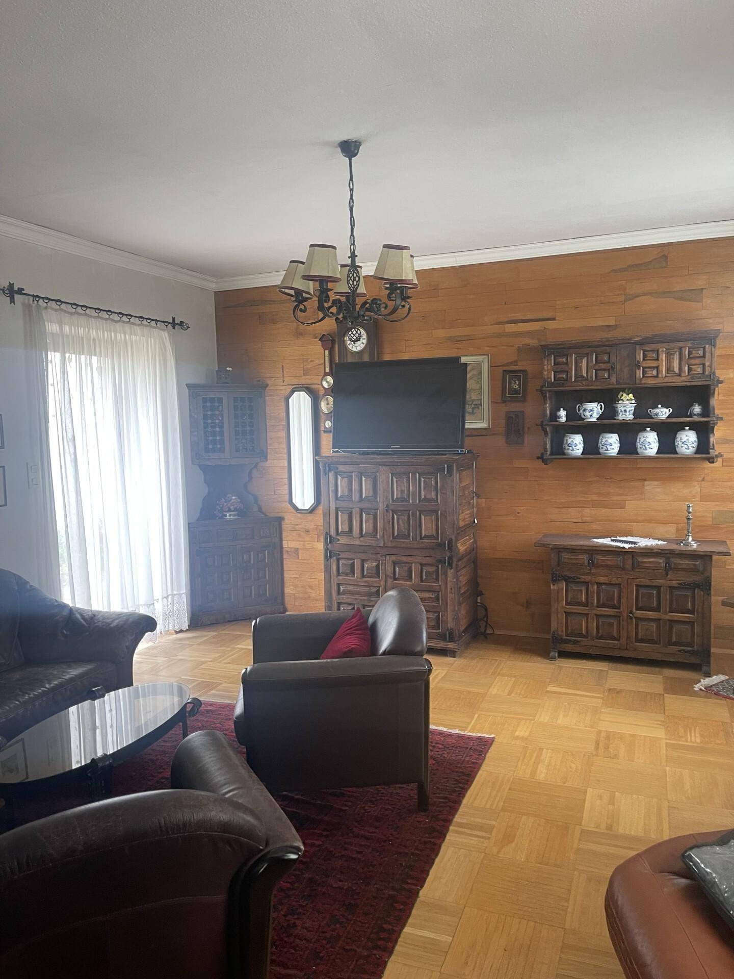 Gemütliches Wohnzimmer im traditionellen Stil mit Holzvertäfelung und Parkettboden.