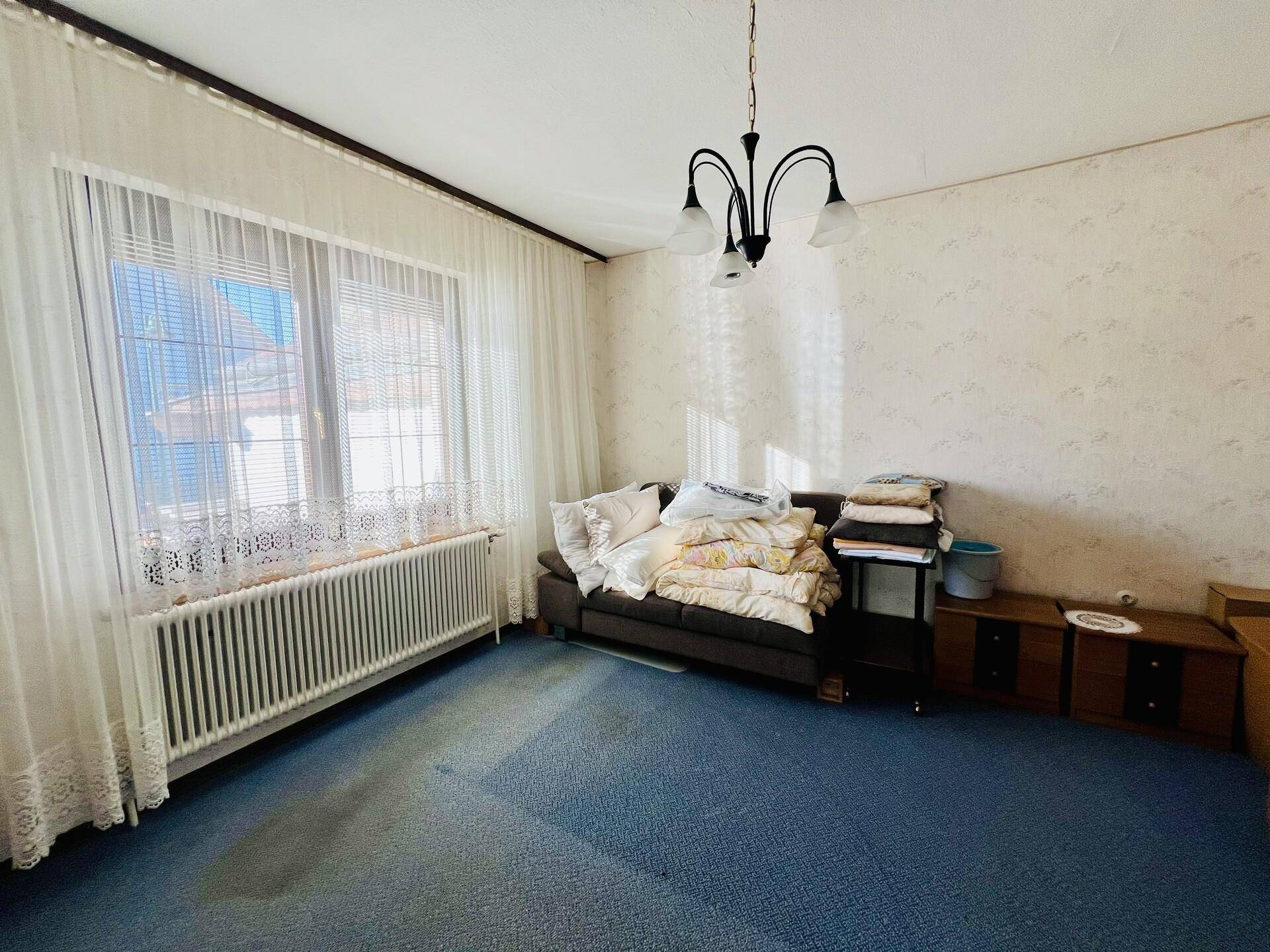 Gemütliches Schlafzimmer mit Fenster, Heizkörper und weichen Vorhängen, ideal zum Entspannen.