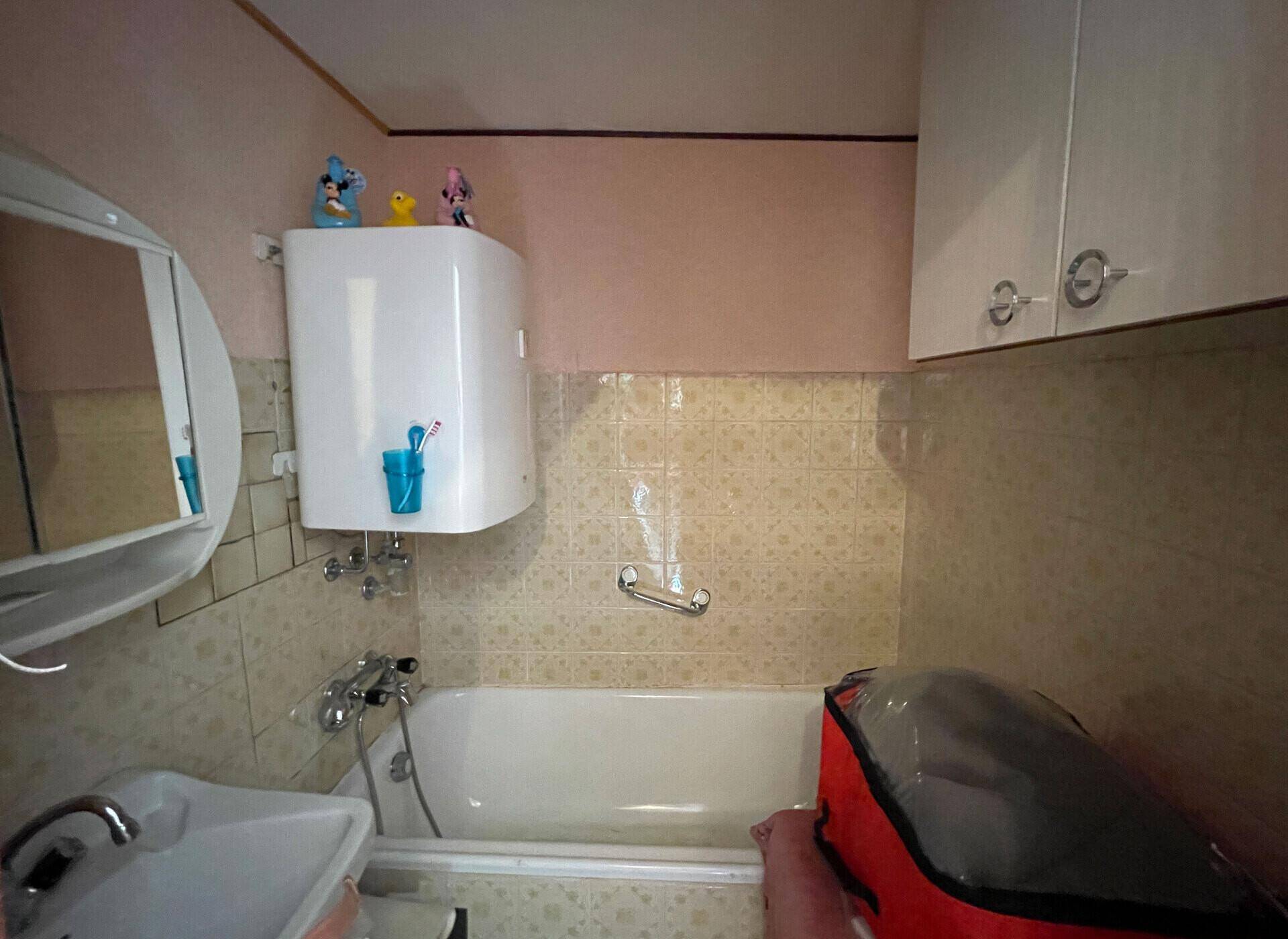 Badezimmer mit Badewanne, Waschbecken und Spiegelschrank in hellem Design.