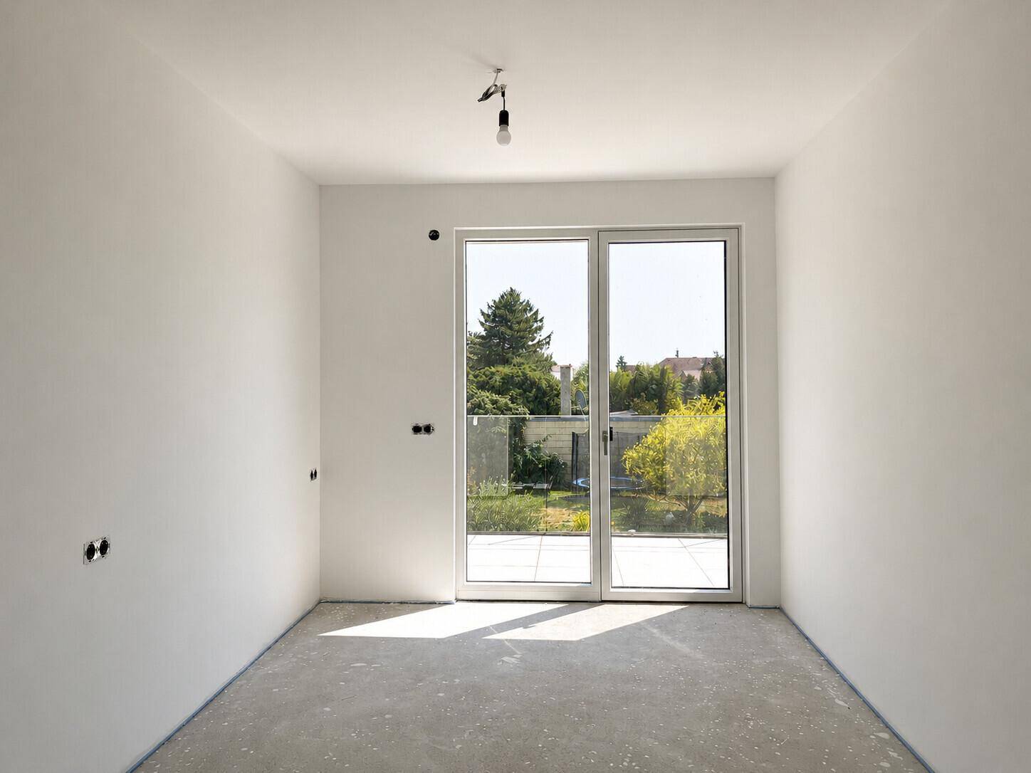 Unfertiges Schlafzimmer mit großem Fenster und Zugang zu einem Außenbereich, bereit für den Ausbau.