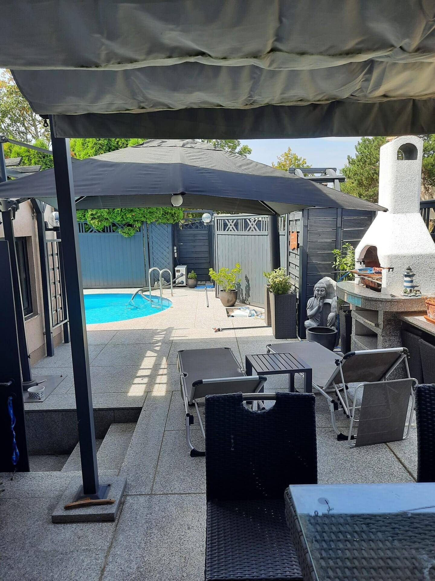 Geräumige Terrasse mit Sitzgelegenheiten, Poolbereich und einer voll ausgestatteten Außenküche mit Grillkamin.