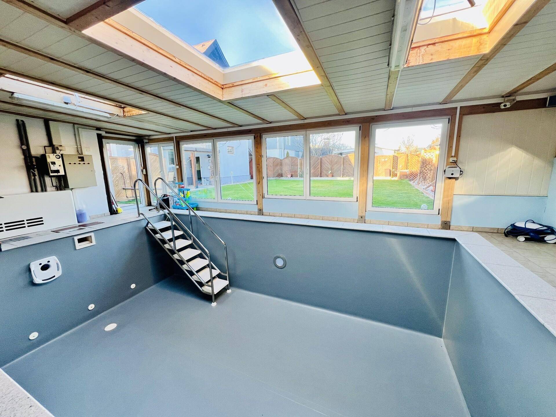 Innenpoolbereich mit großen Fenstern und Oberlichtern, der Pool ist derzeit leer.