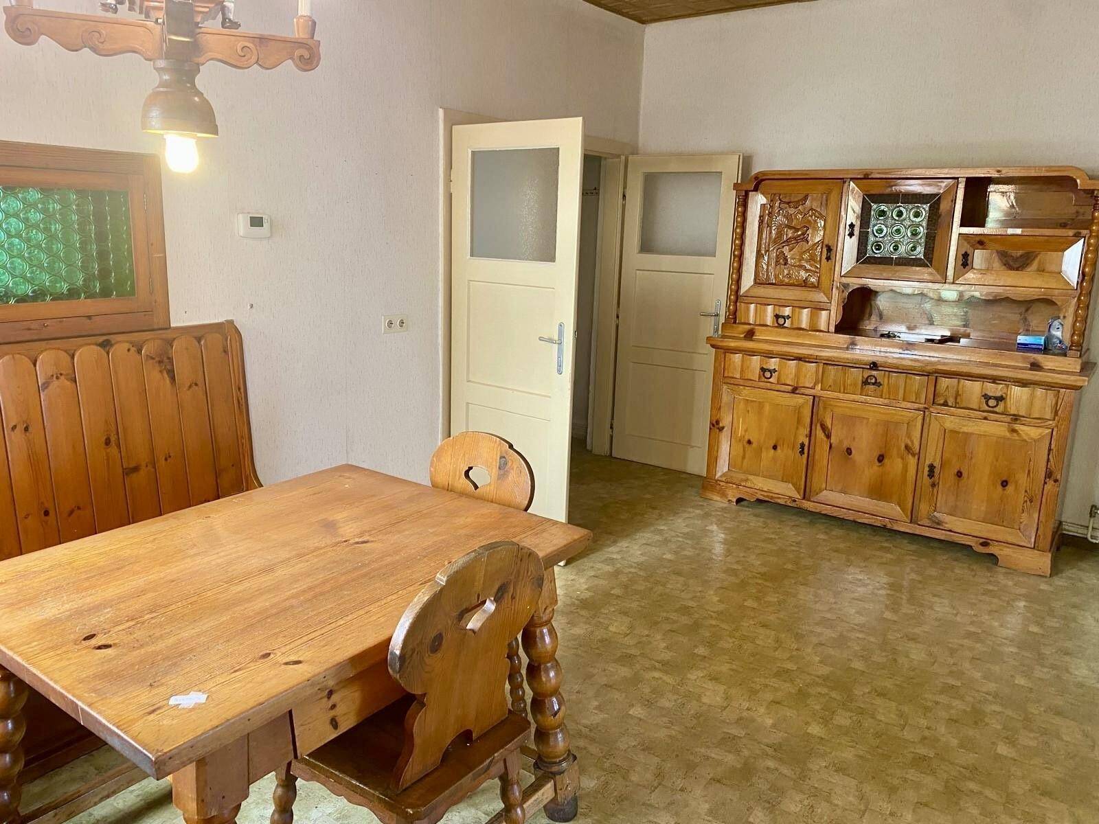 Gemütliche Küche mit traditionellen Holzmöbeln, Esstisch und einem verzierten Schrank.