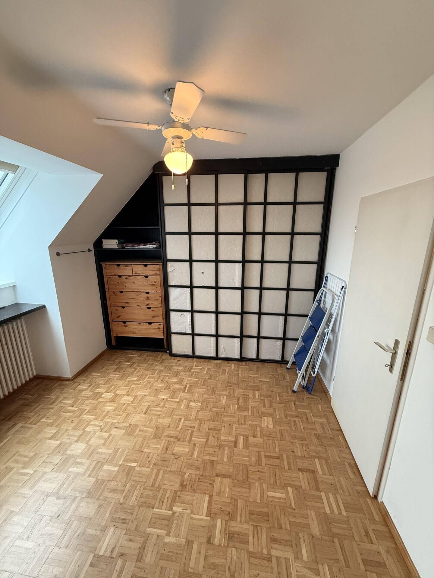 Schlafzimmer mit Dachschräge, Parkettboden und praktischem Einbauschrank.