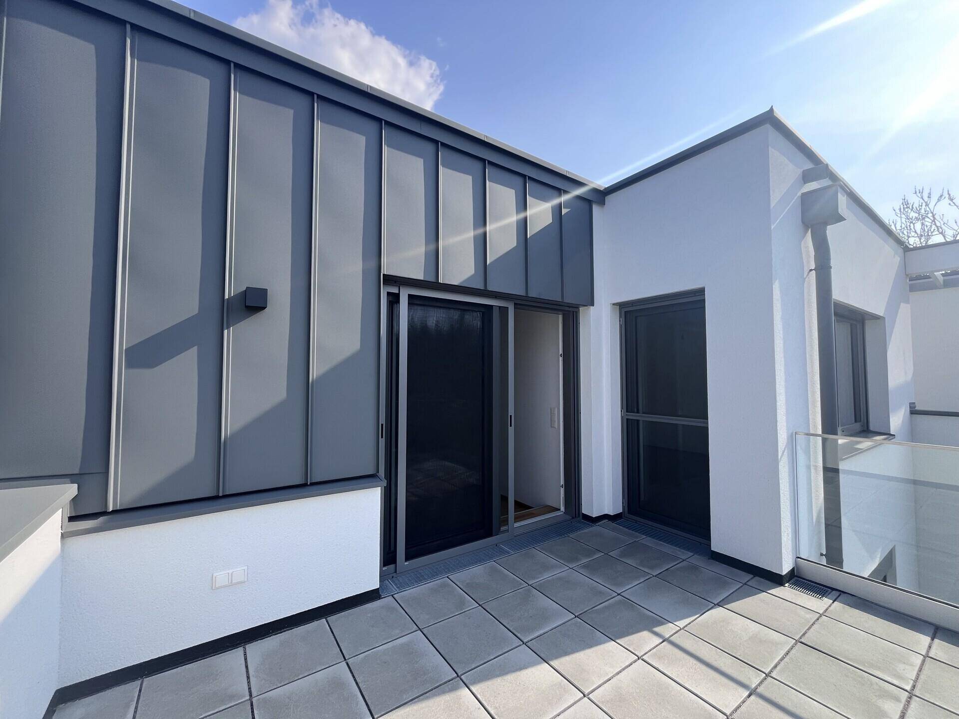 Obergeschoss-Balkon mit Schiebetüren und moderner Verkleidung, ideal für Entspannung.