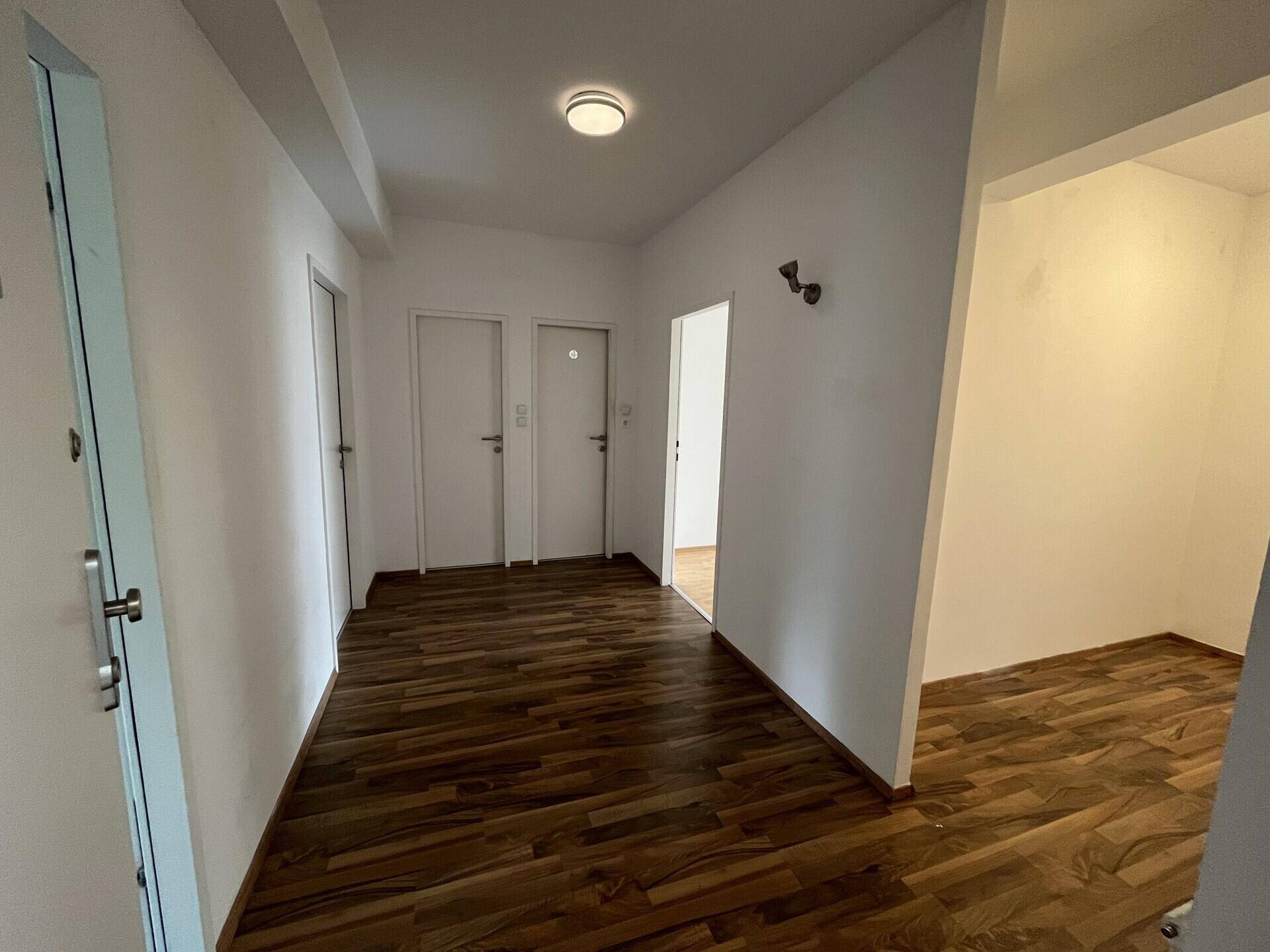 Heller Flur mit modernem Laminatboden und weißen Türen.