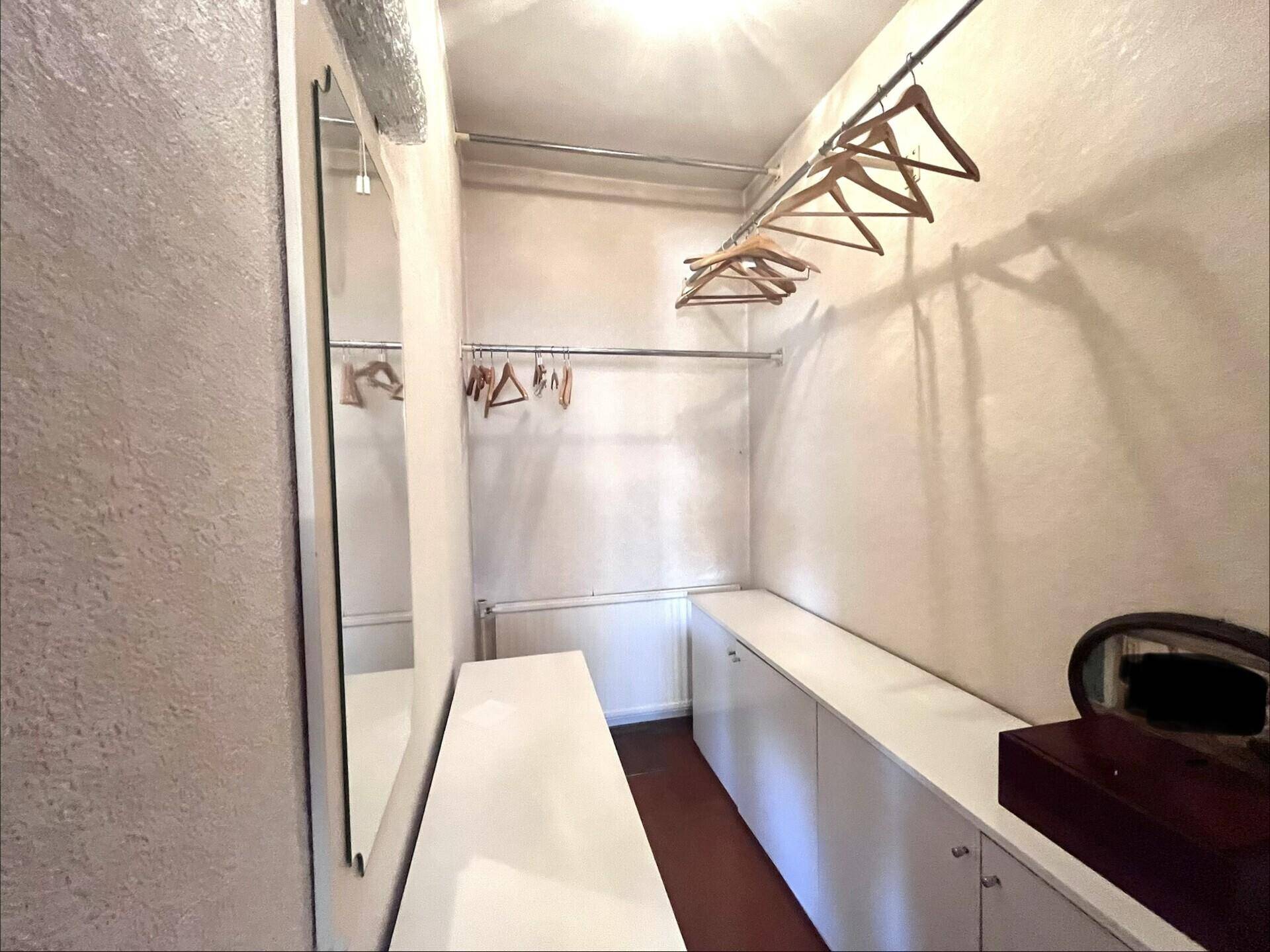 Praktischer begehbarer Kleiderschrank oder Abstellraum mit Regalen und Kleiderstangen.