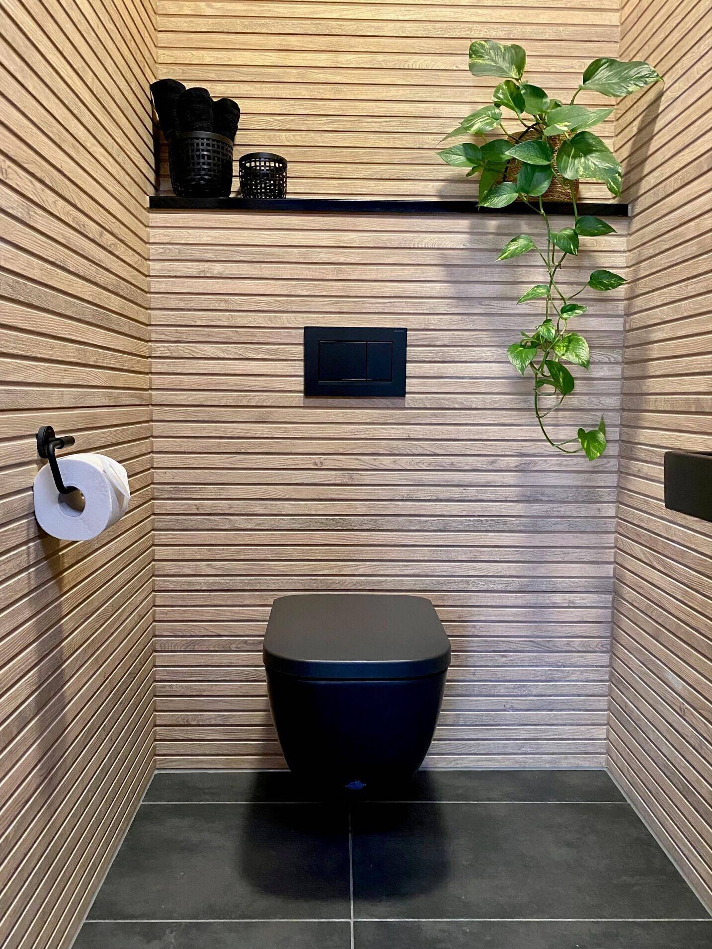 Modernes Gäste-WC mit schwarzen Armaturen, Holzlamellenwänden und dunklen Bodenfliesen.