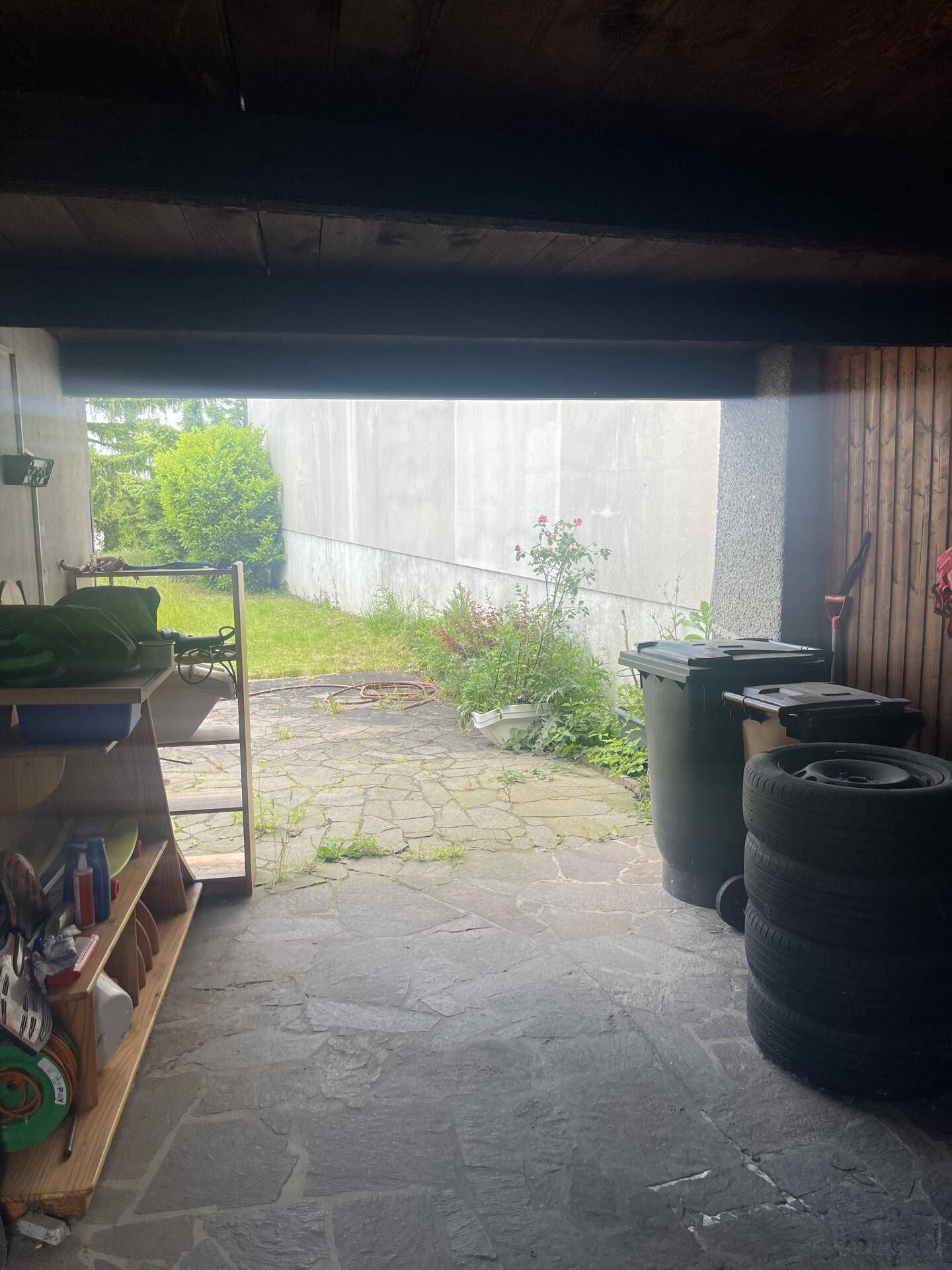 Geräumige Garage mit Lagerregalen und Blick auf den hinteren Gartenbereich.