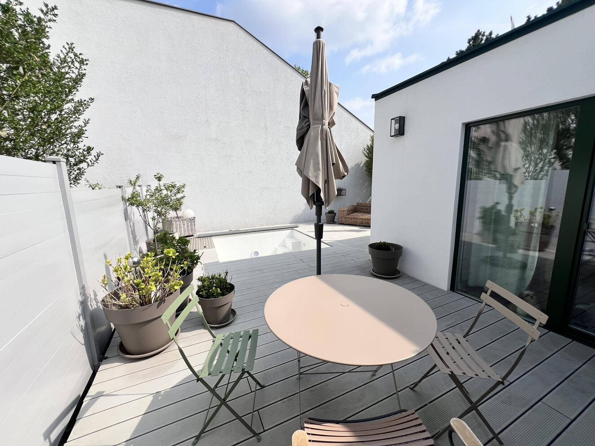 Gemütliche Terrasse mit Esstisch und Stühlen, ideal für Mahlzeiten im Freien.