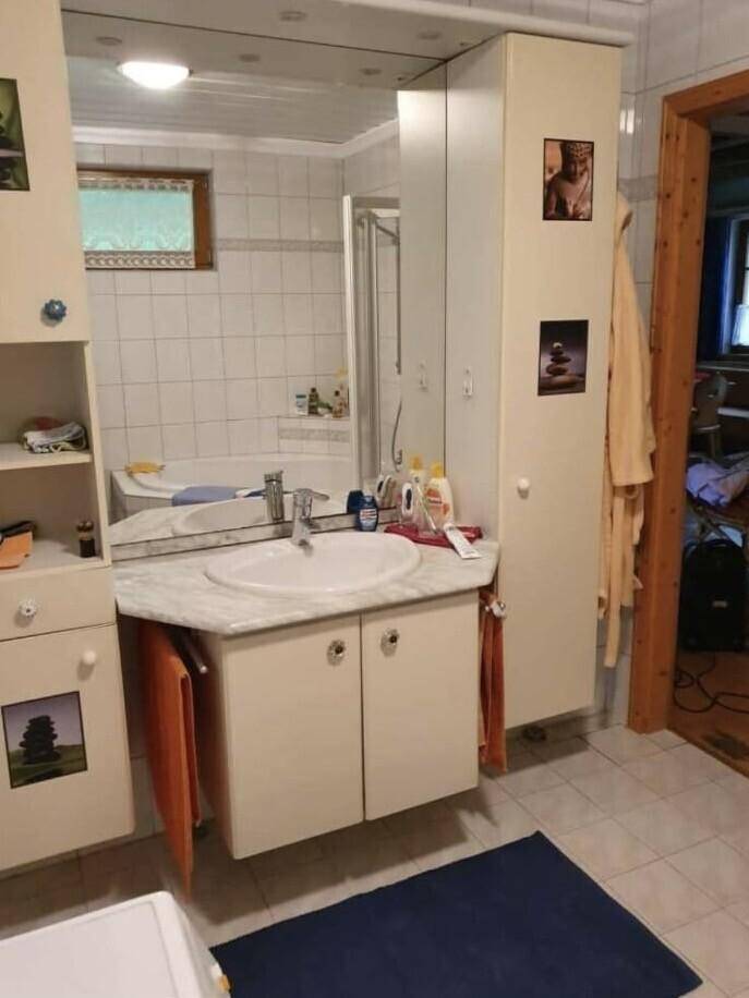 Helles Badezimmer mit Waschtisch, Spiegelschrank und weißen Fliesen.