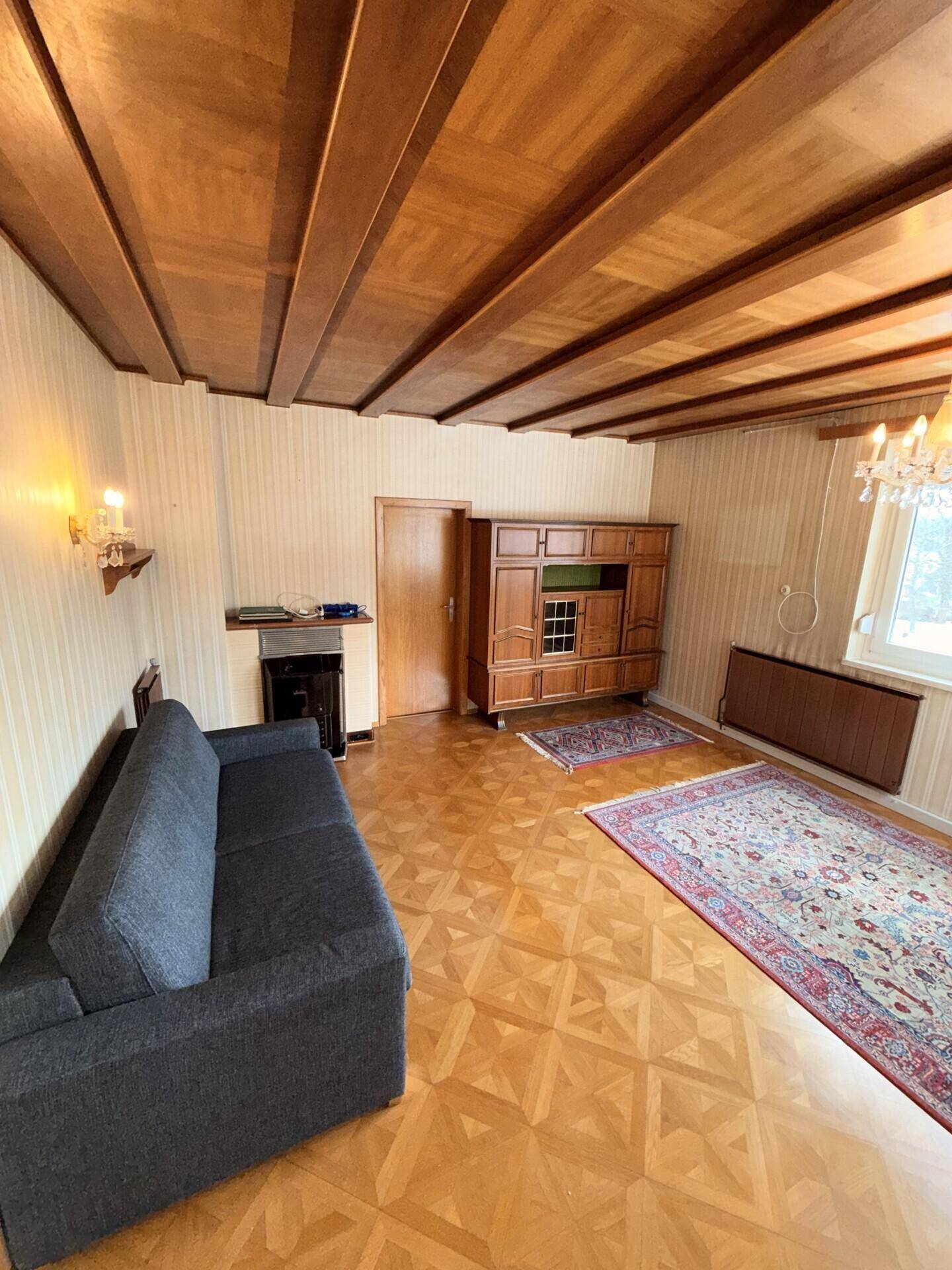 Wohnzimmer mit Parkettboden, Holzdecke und traditionellen Möbeln in gutem Zustand.