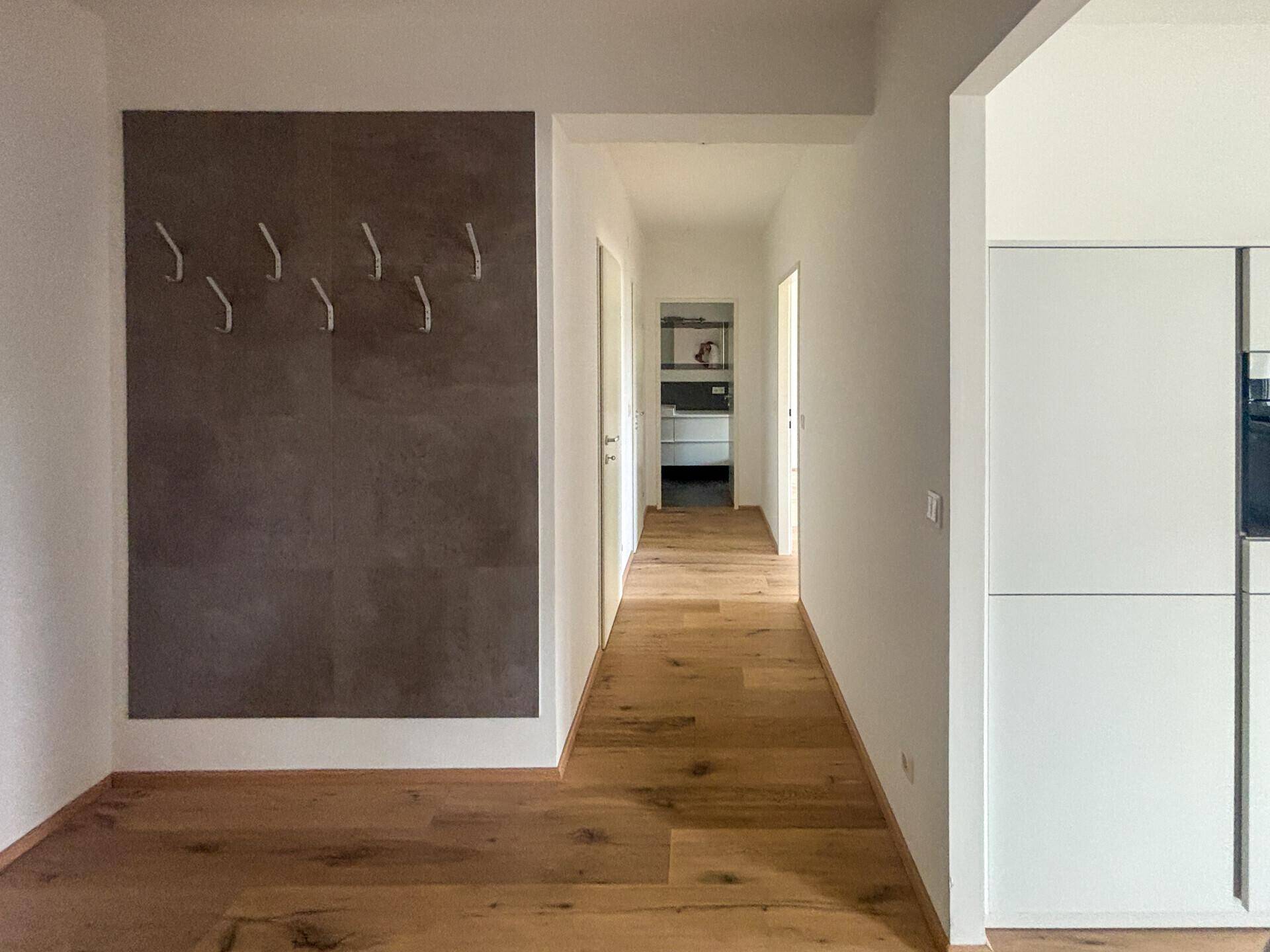 Langer Flur mit Holzboden, der zu weiteren Räumen der Wohnung führt.