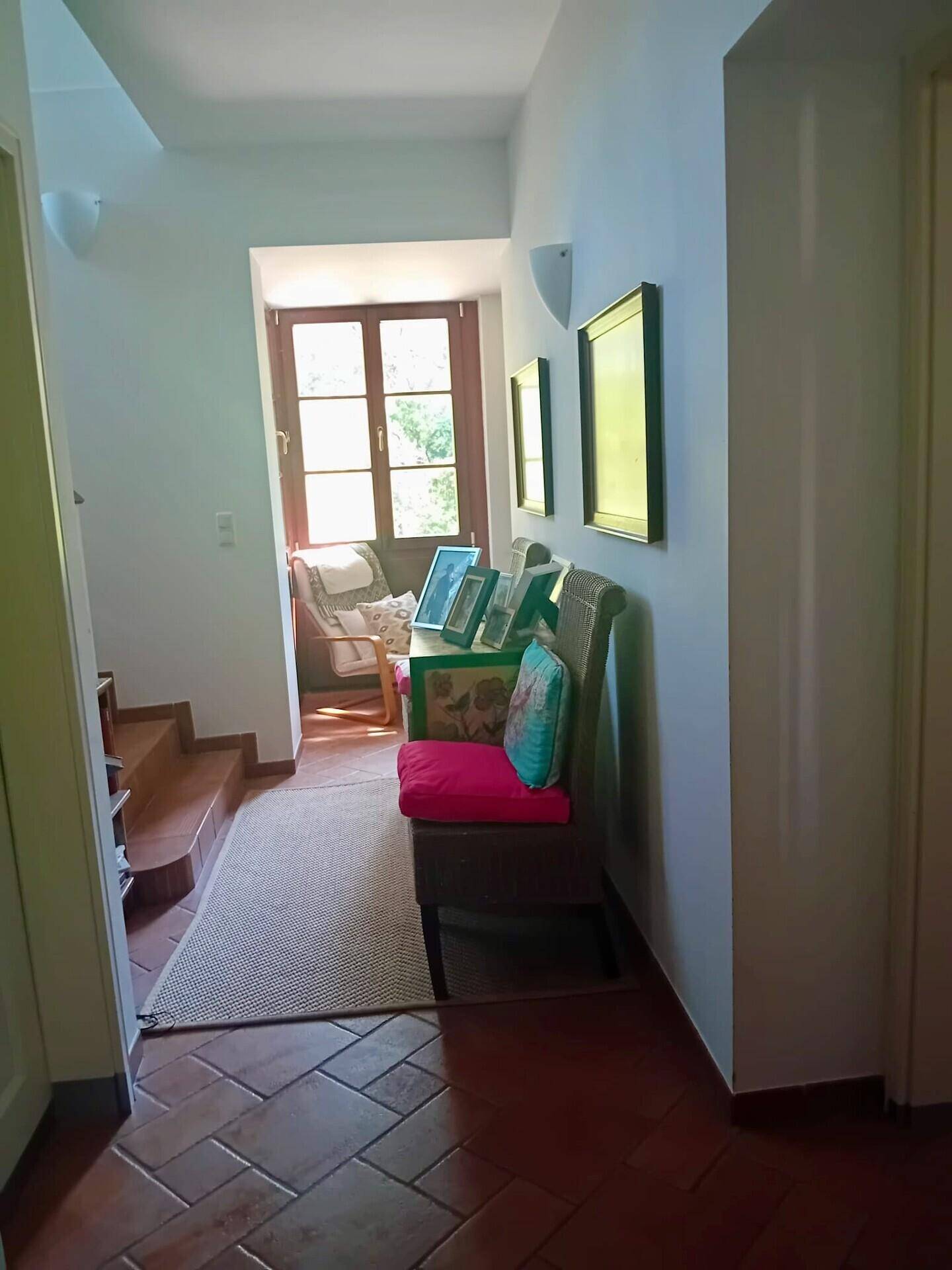 Heller Flur mit Terrakottaboden, weißen Wänden und einem Fenster am Ende, das Licht hereinlässt.