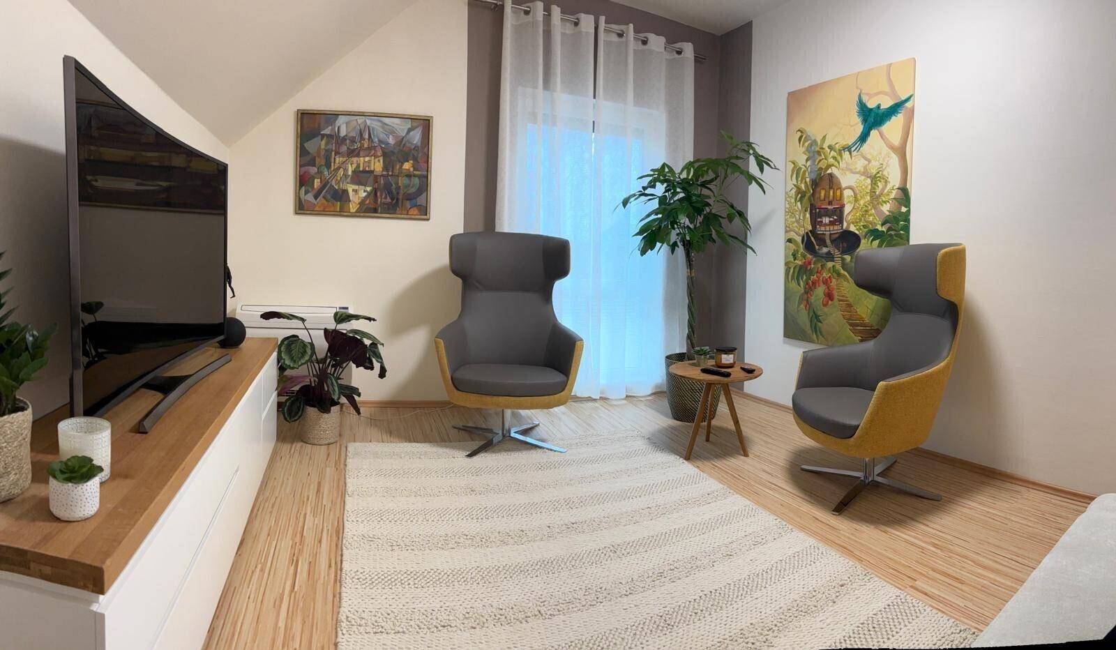 Gemütlicher Medienraum mit modernen Sesseln, großem Fernseher und Laminatboden unter Dachschrägen.