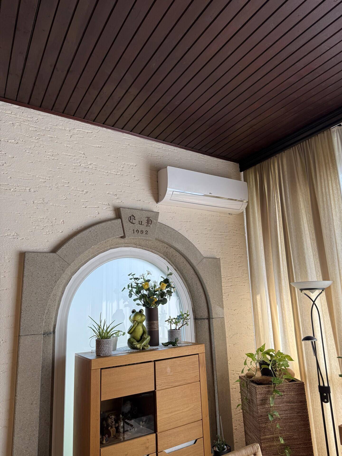 Innenraum mit dekorativem Bogen, Holzdecke und Klimaanlage an der Wand.