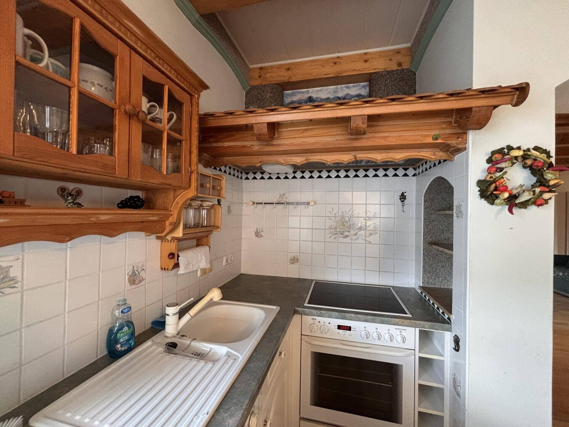 Detailansicht der Küche mit Herd, Backofen, Spüle und traditionellen Fliesen.