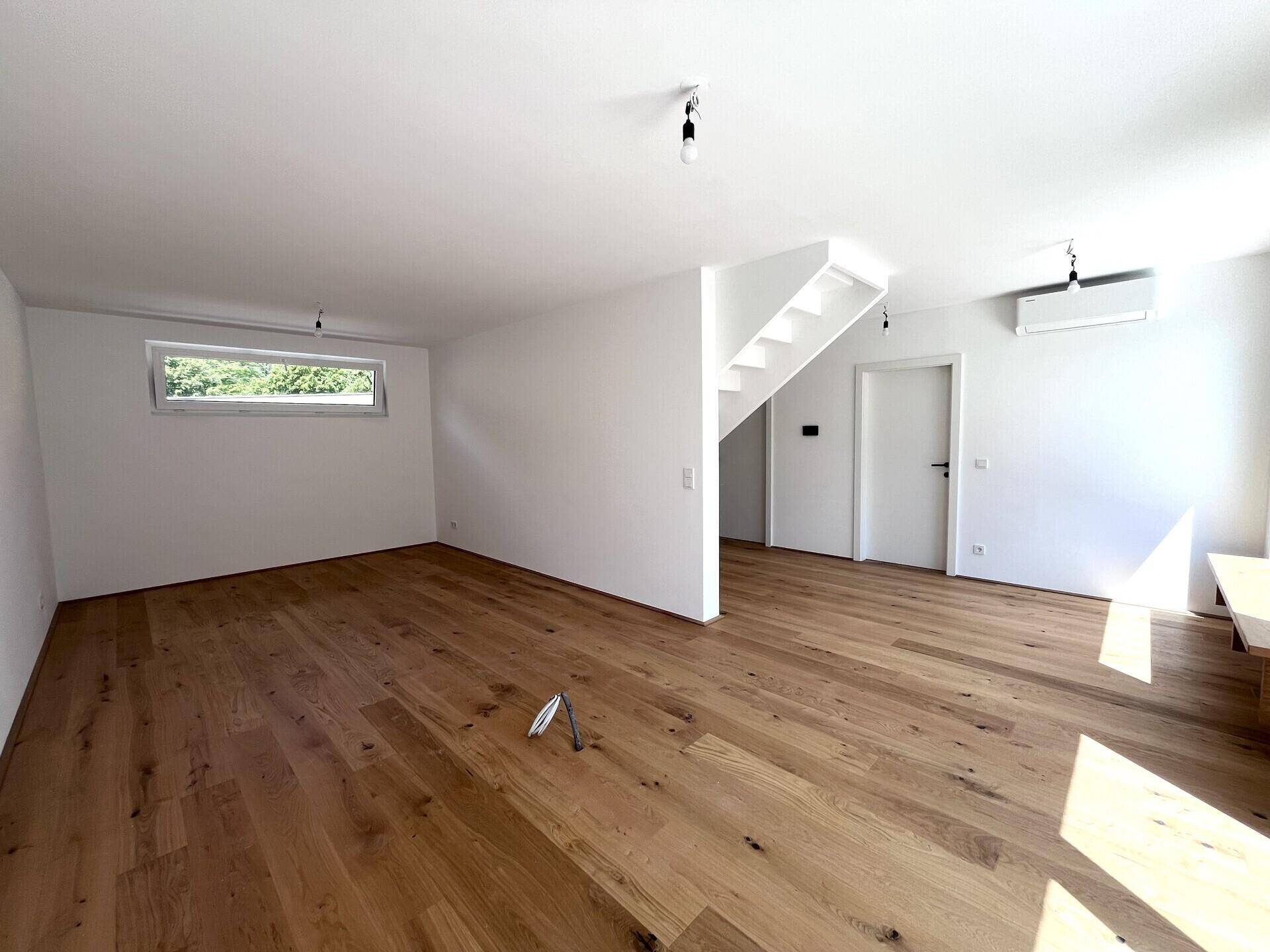 Geräumiger Wohnbereich mit Holzboden, Treppe, Klimaanlage und viel natürlichem Licht.