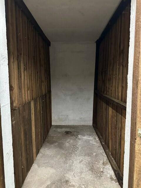 Kleiner Abstellraum mit Holzlattenwänden und Betonboden, ideal für zusätzlichen Stauraum.