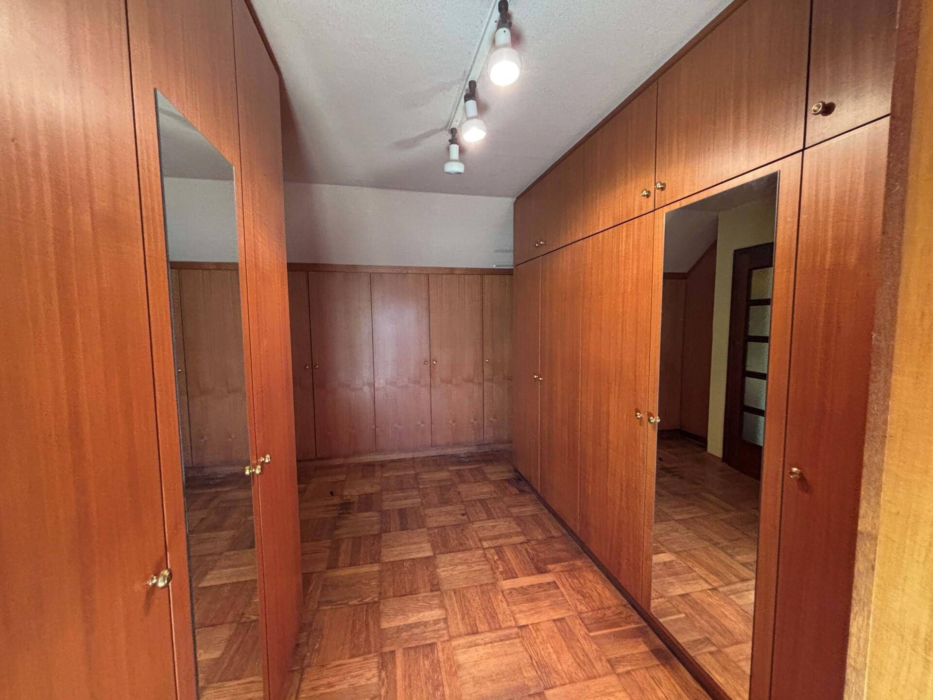 Ankleidezimmer mit Holzboden und durchgehenden Einbauschränken mit Spiegeltüren.