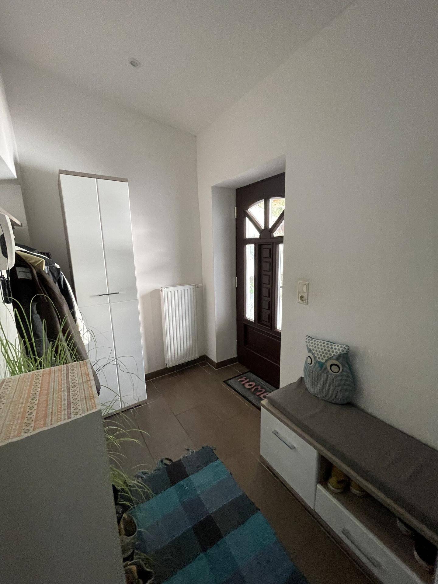 Heller Eingangsbereich mit Garderobe, Schuhbank und dunklem Holzboden.