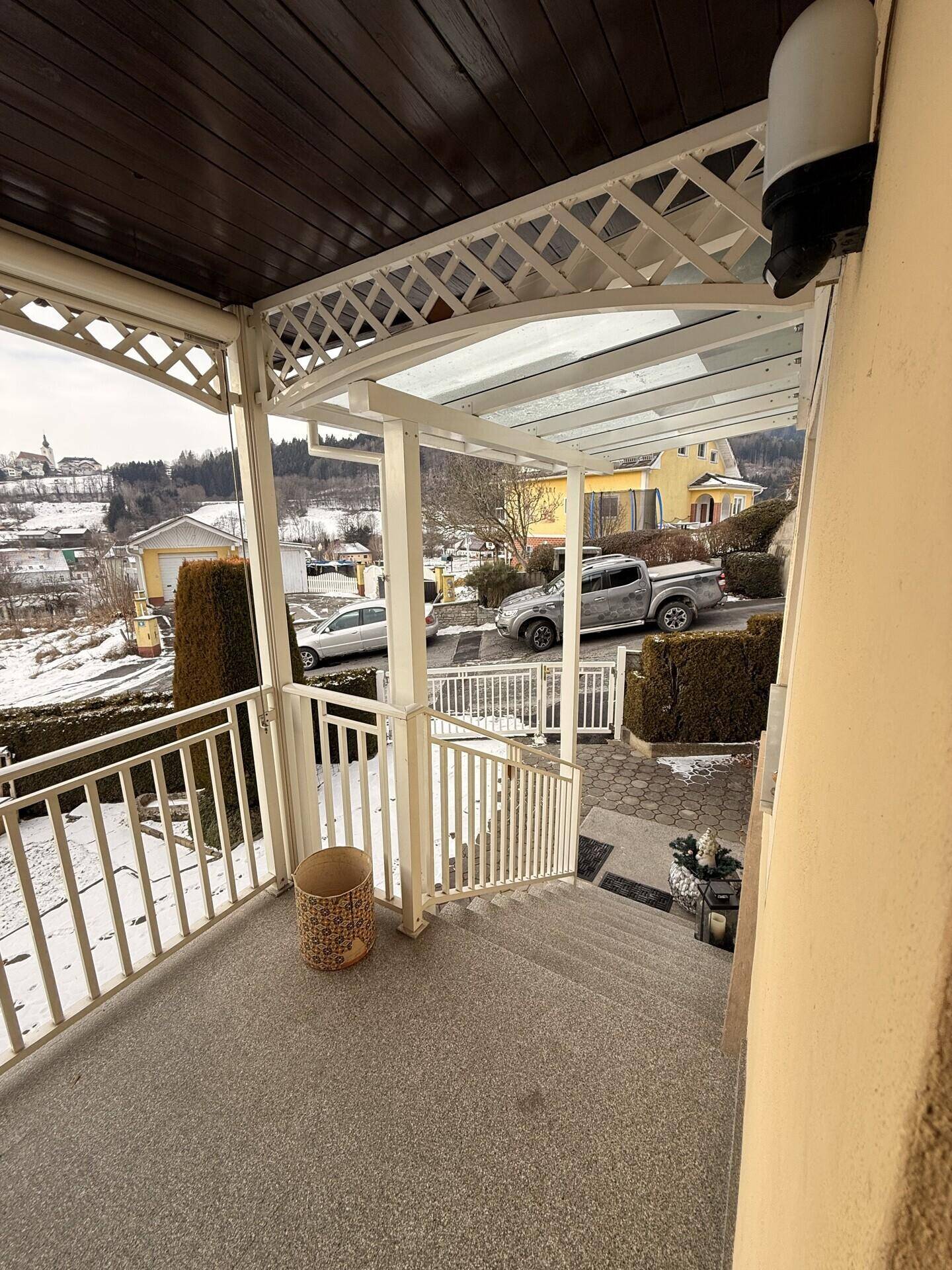 Überdachter Balkon im Winter mit Blick auf die verschneite Ortschaft.