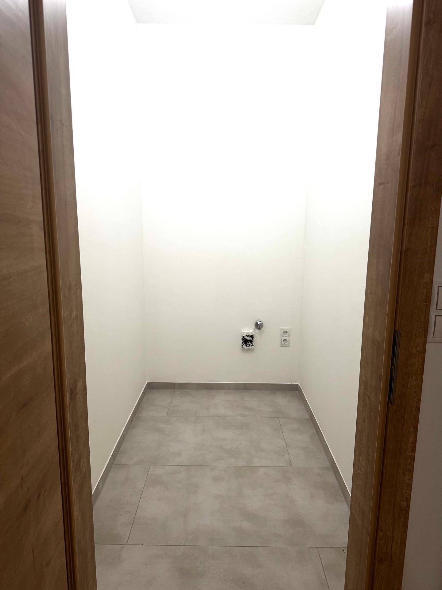 Praktischer Hauswirtschaftsraum mit Fliesenboden und Anschlüssen für Waschmaschine oder Trockner.