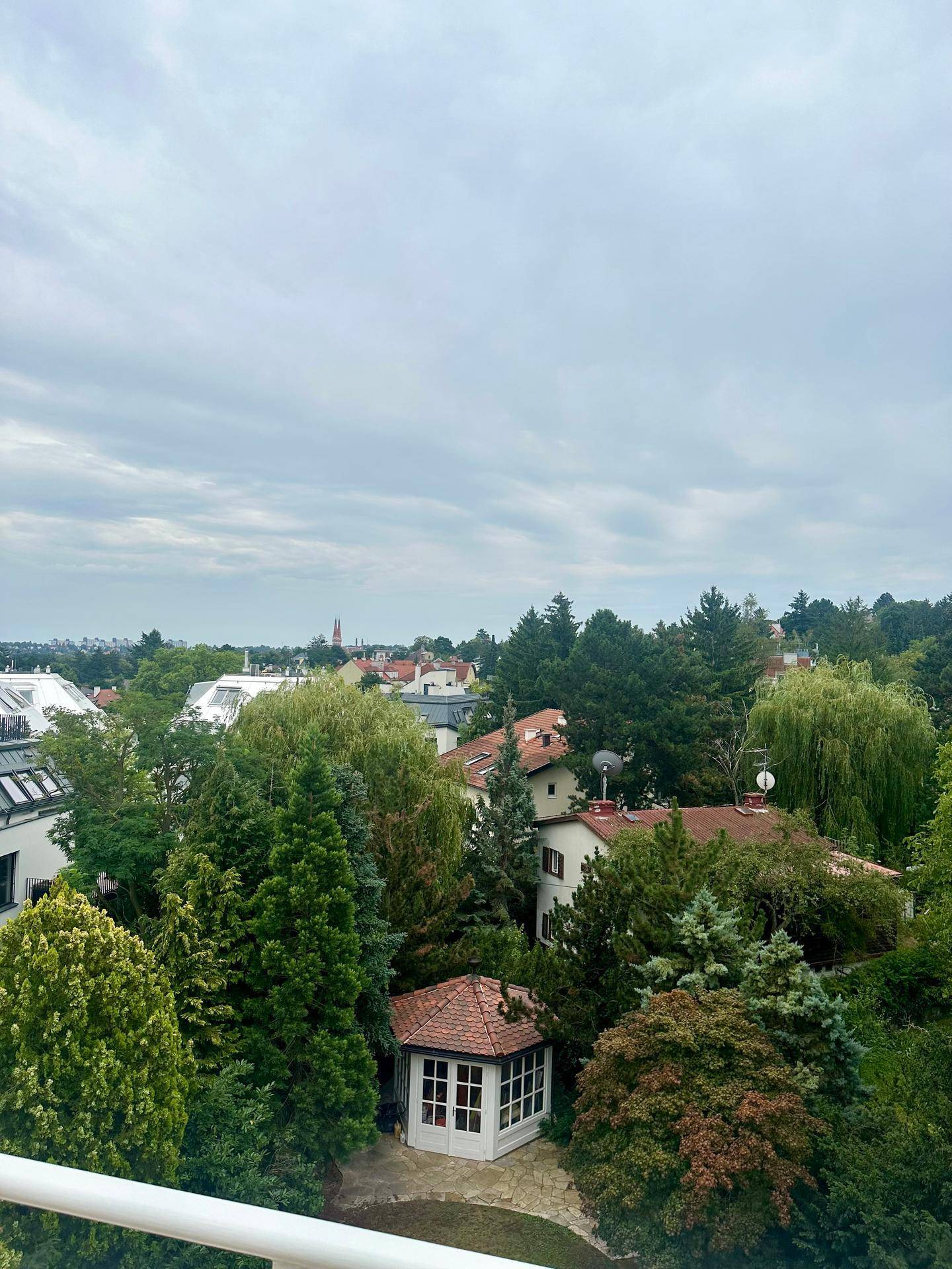 Weitläufiger Blick über eine grüne Wohngegend mit vielen Bäumen und Häusern, inklusive eines Gartenpavillons.