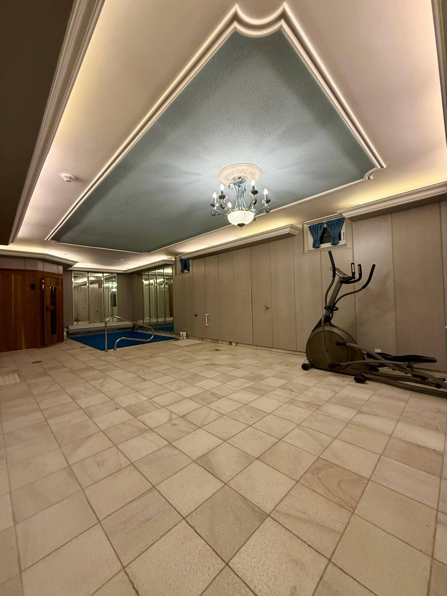 Geräumiger Wellnessbereich mit Innenpool, Fitnessgerät und eleganter Deckenbeleuchtung.