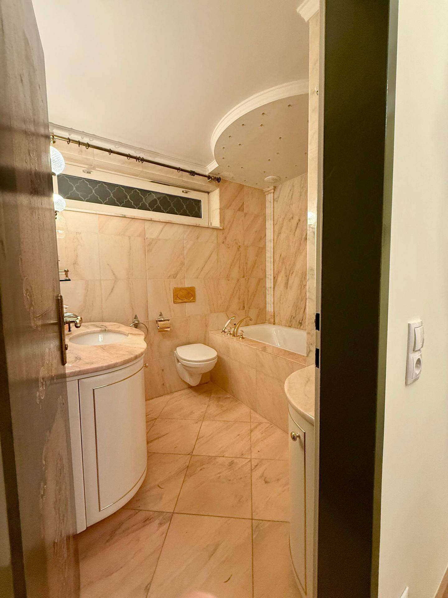 Elegantes Badezimmer mit Marmorfliesen, Doppelwaschbecken und integrierter Badewanne.
