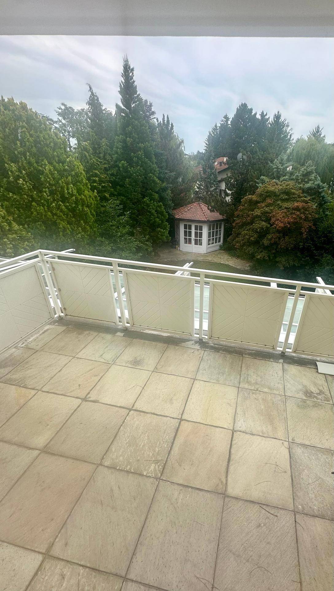Geräumiger Balkon mit Fliesenboden und weitem Blick ins Grüne mit Gartenhaus.