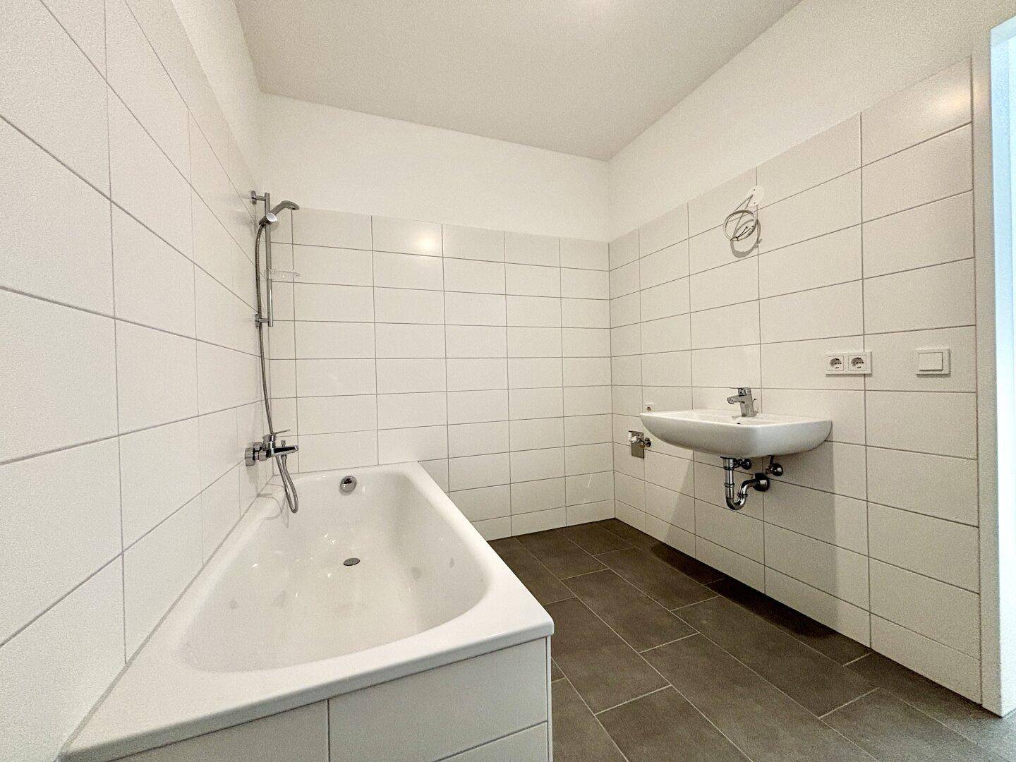 Modernes Badezimmer mit weißen Wandfliesen, einer Badewanne und einem Waschbecken.