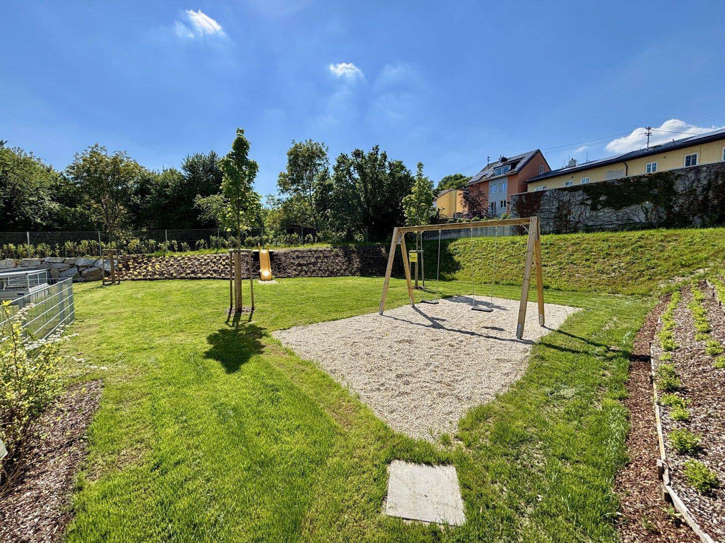 Gepflegter Gartenbereich mit Schaukeln und Rutsche, ideal für Kinder zum Spielen im Freien.